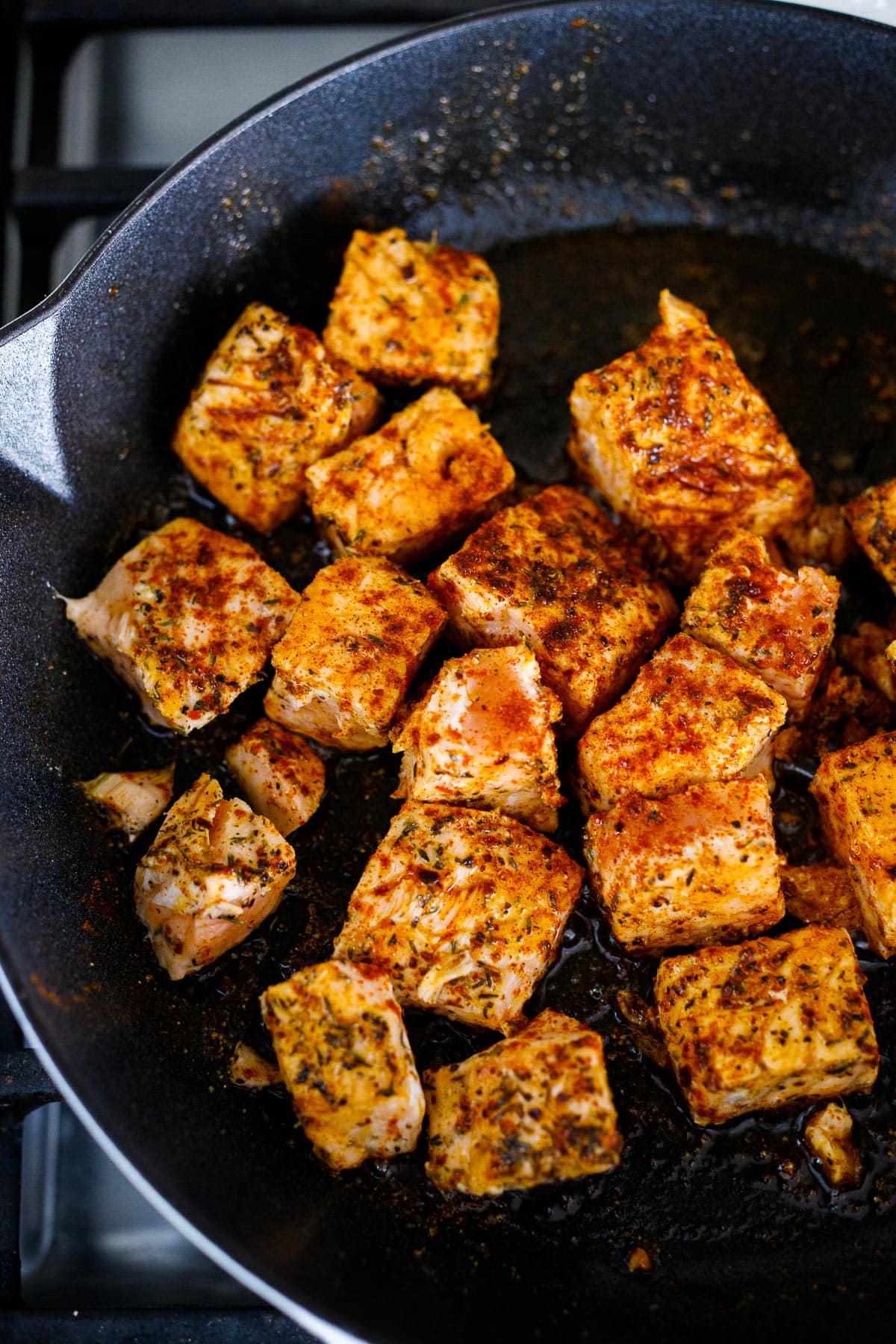 Salmon being seared in a  skillet. 