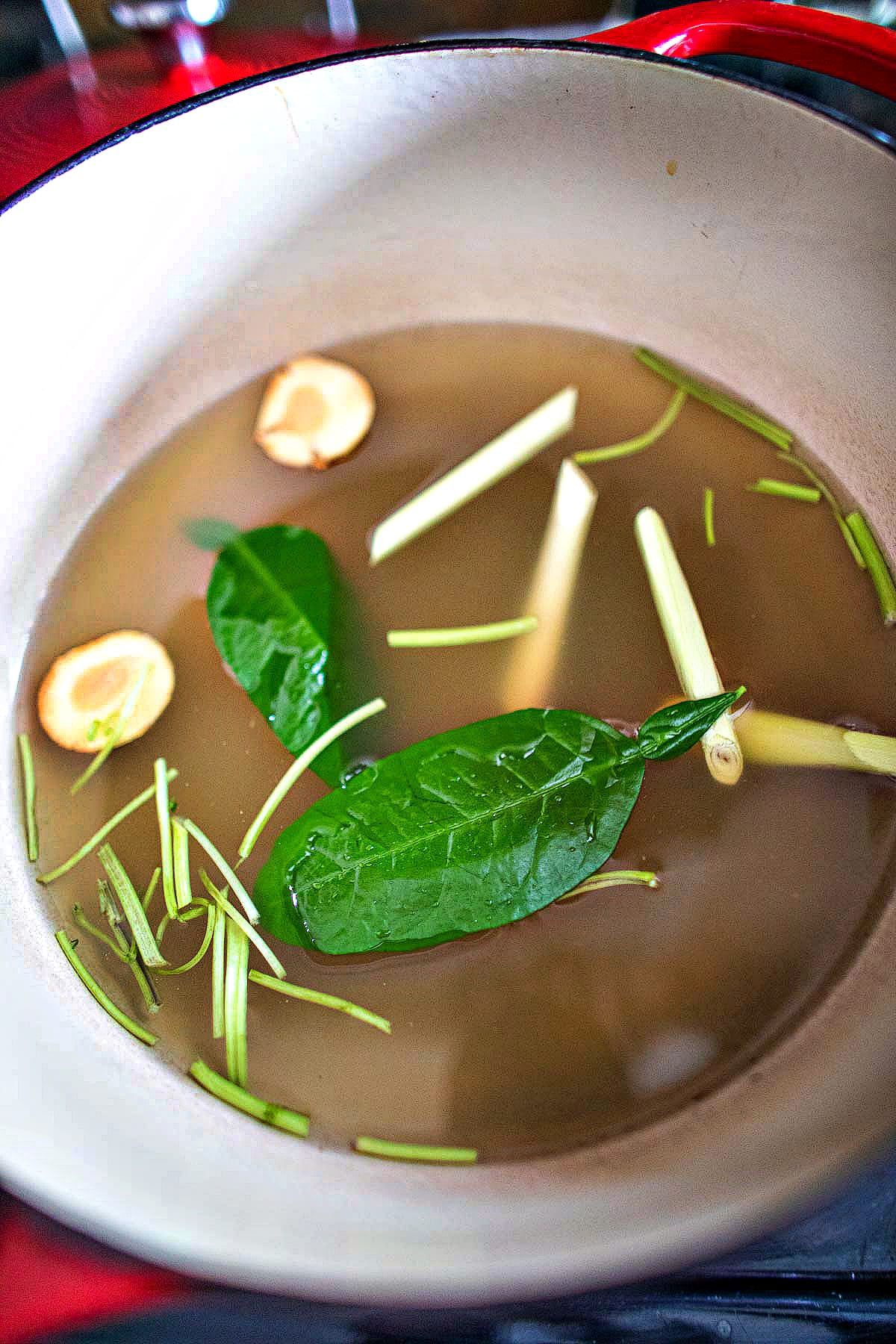 Herbs and stock in a soup pot on the stove.