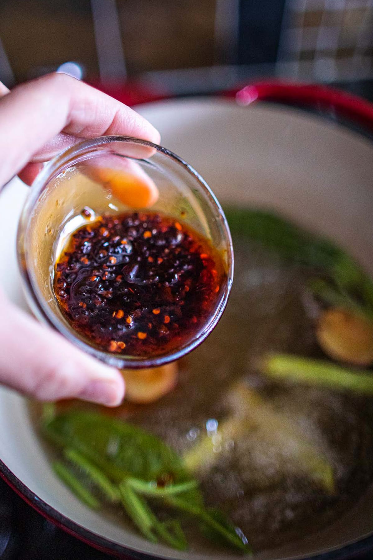 Pouring chili paste for Tom Yum soup into a soup pot.