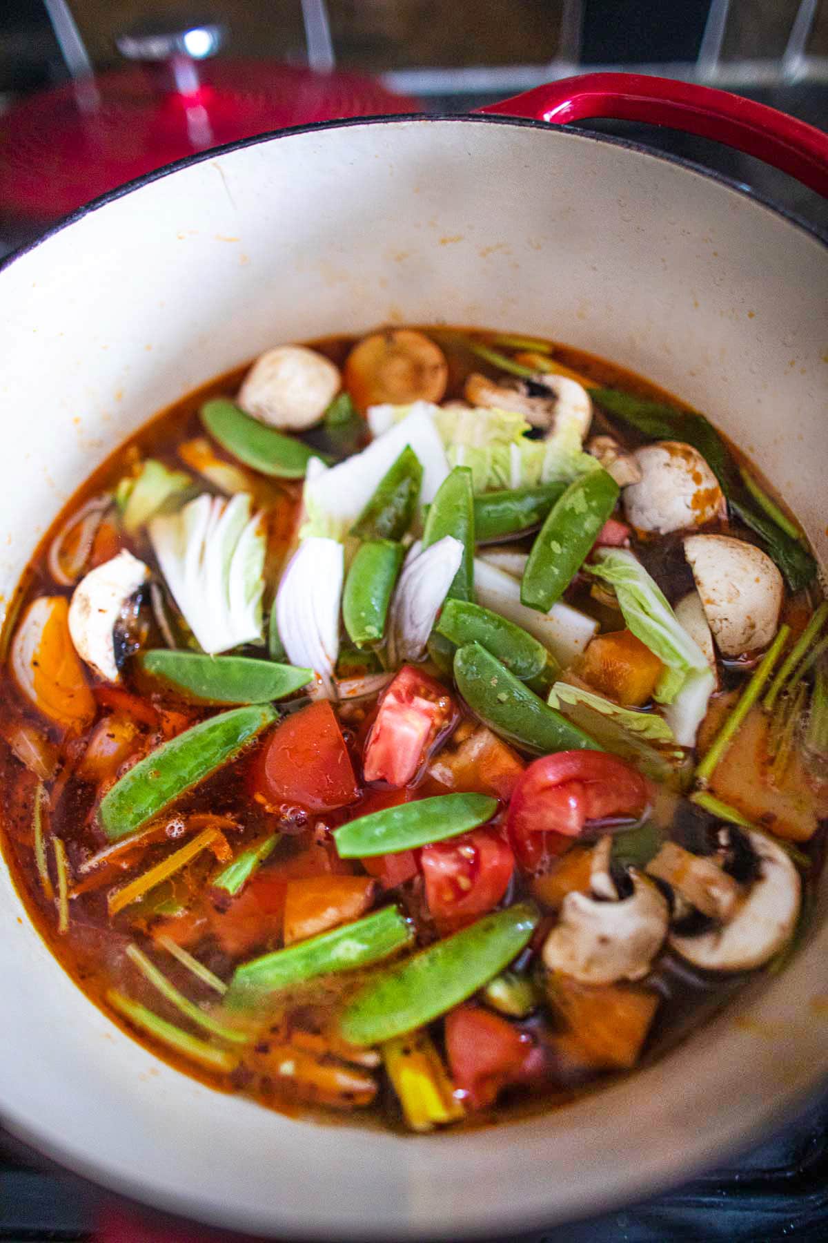 Tofu in Tom Yum soup with vegetables in a soup pot.