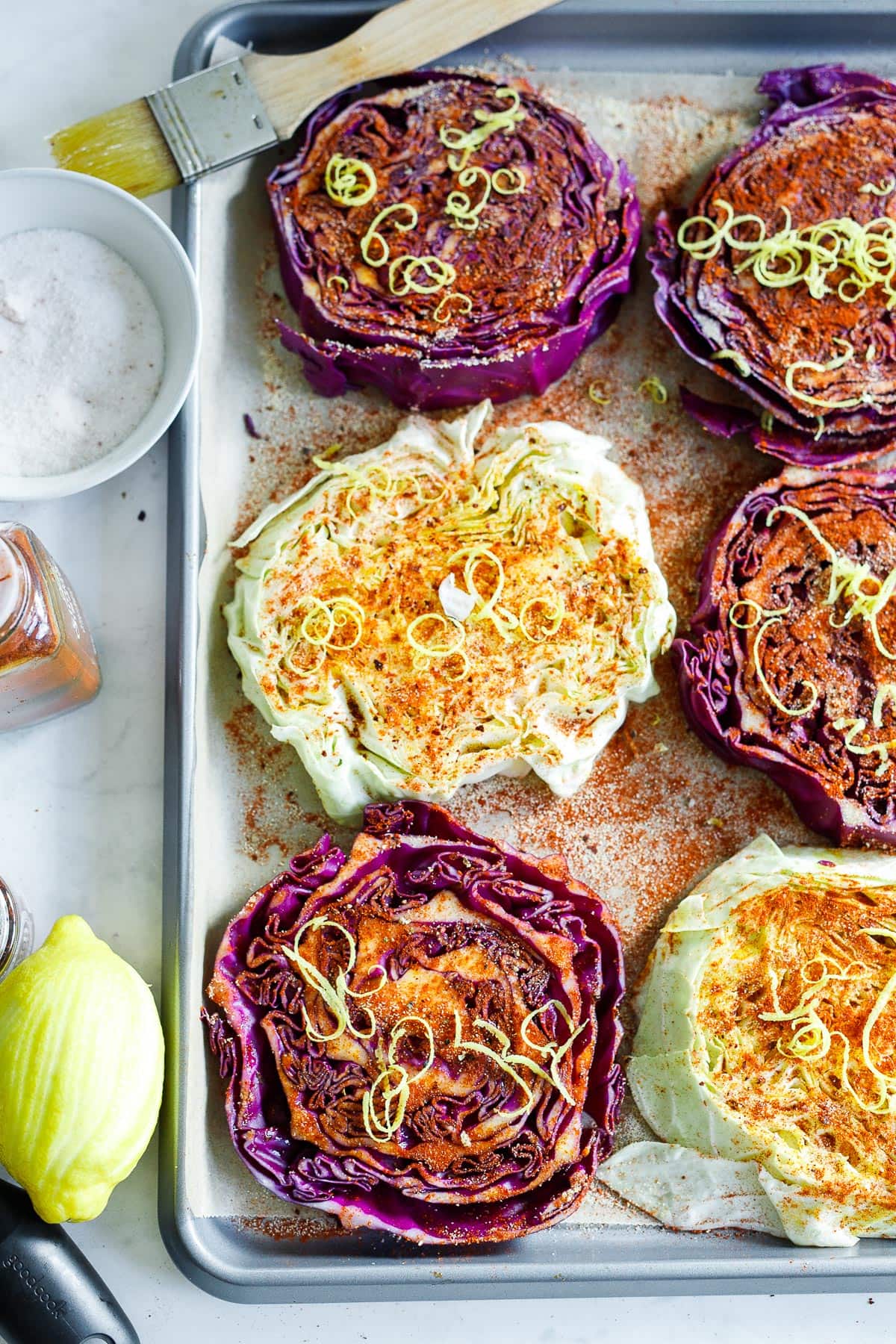 Seasoned cabbage steaks on a sheet pan.