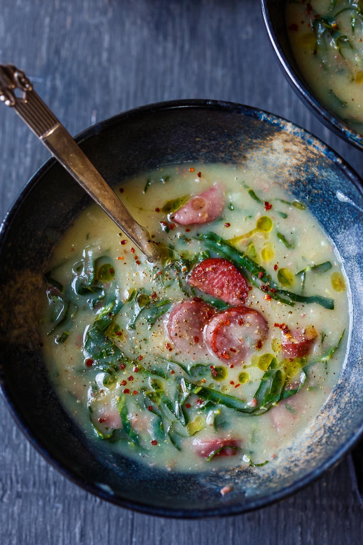 This Portuguese soup called Caldo Verde has a luscious creamy potato base, with collard green ribbons, and smoked sausage. A delicious one-pot meal that is vegan-adaptable!