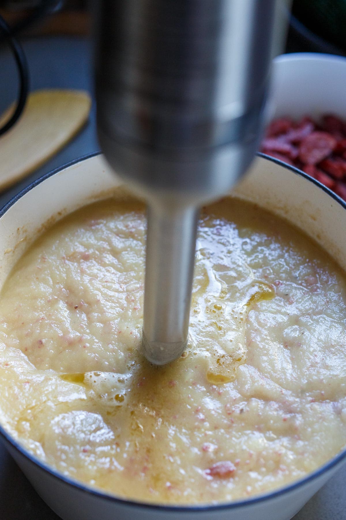 Blending the soup with an immersion blender.