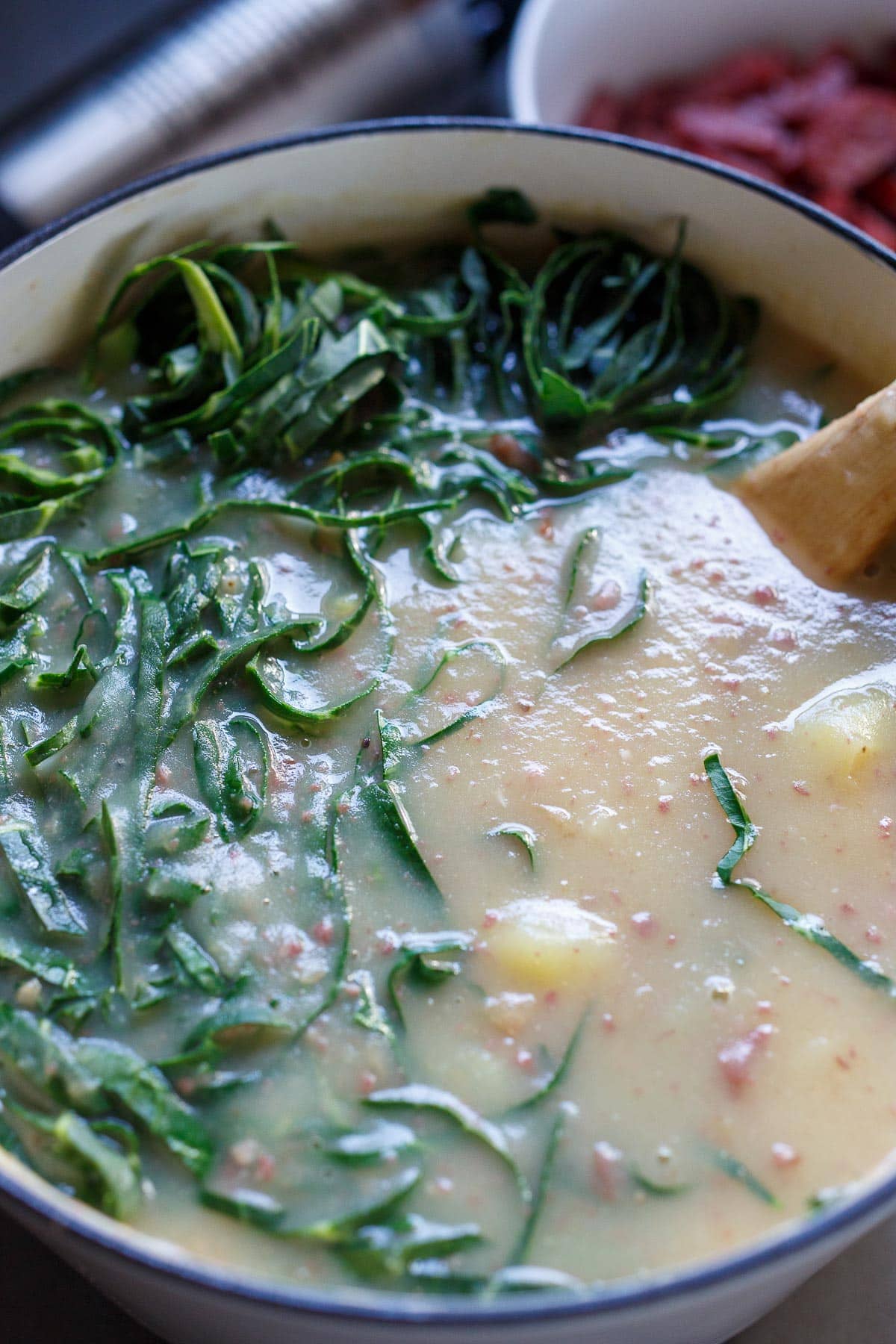 Adding collard greens into the soup.