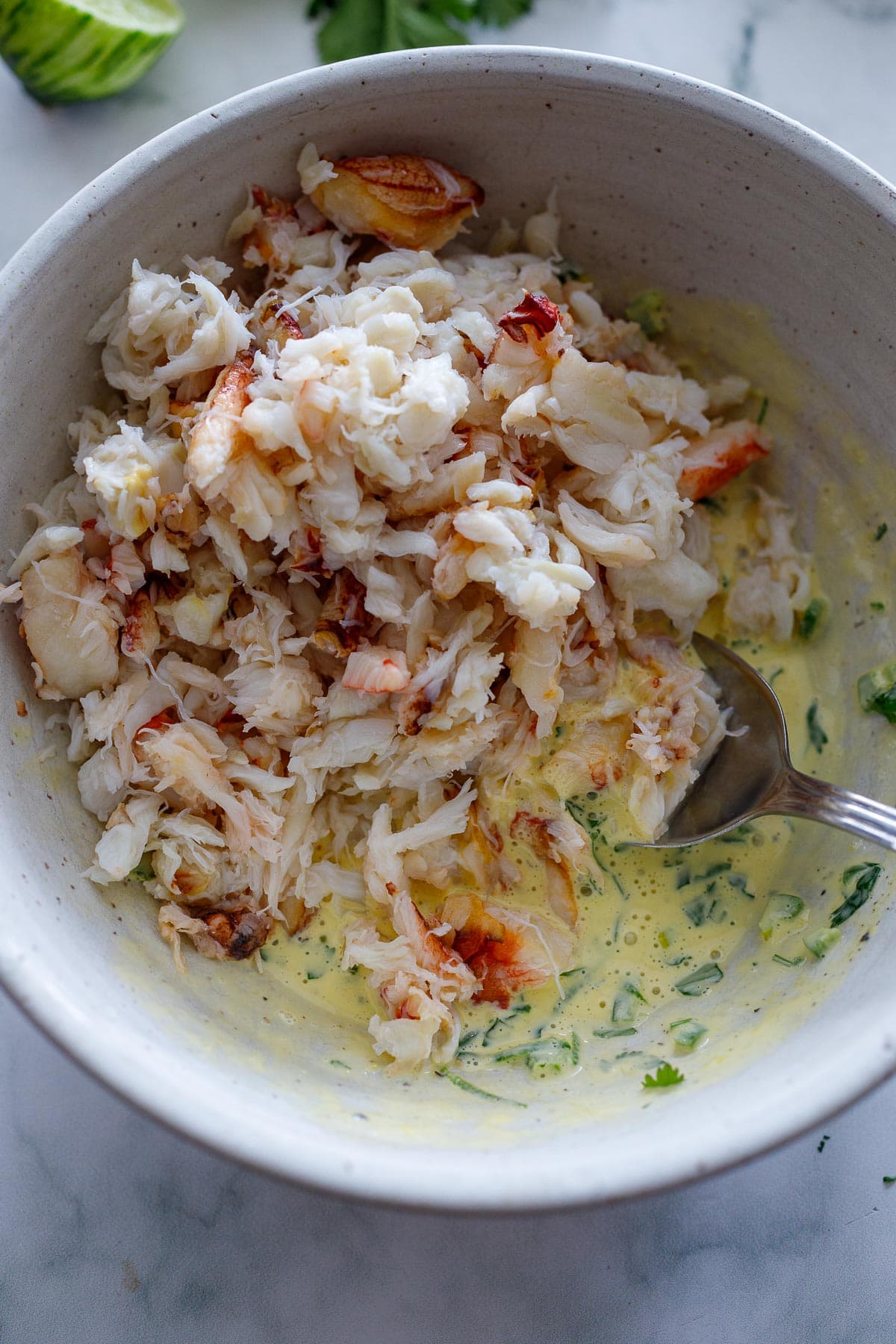 Folding in the fresh crab into the whisked ingredients in a bowl. 
