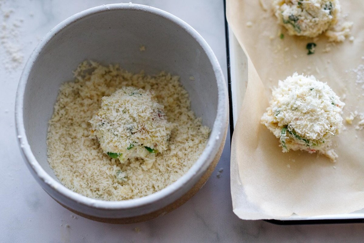Dredging crab cakes in panko bread crumbs.