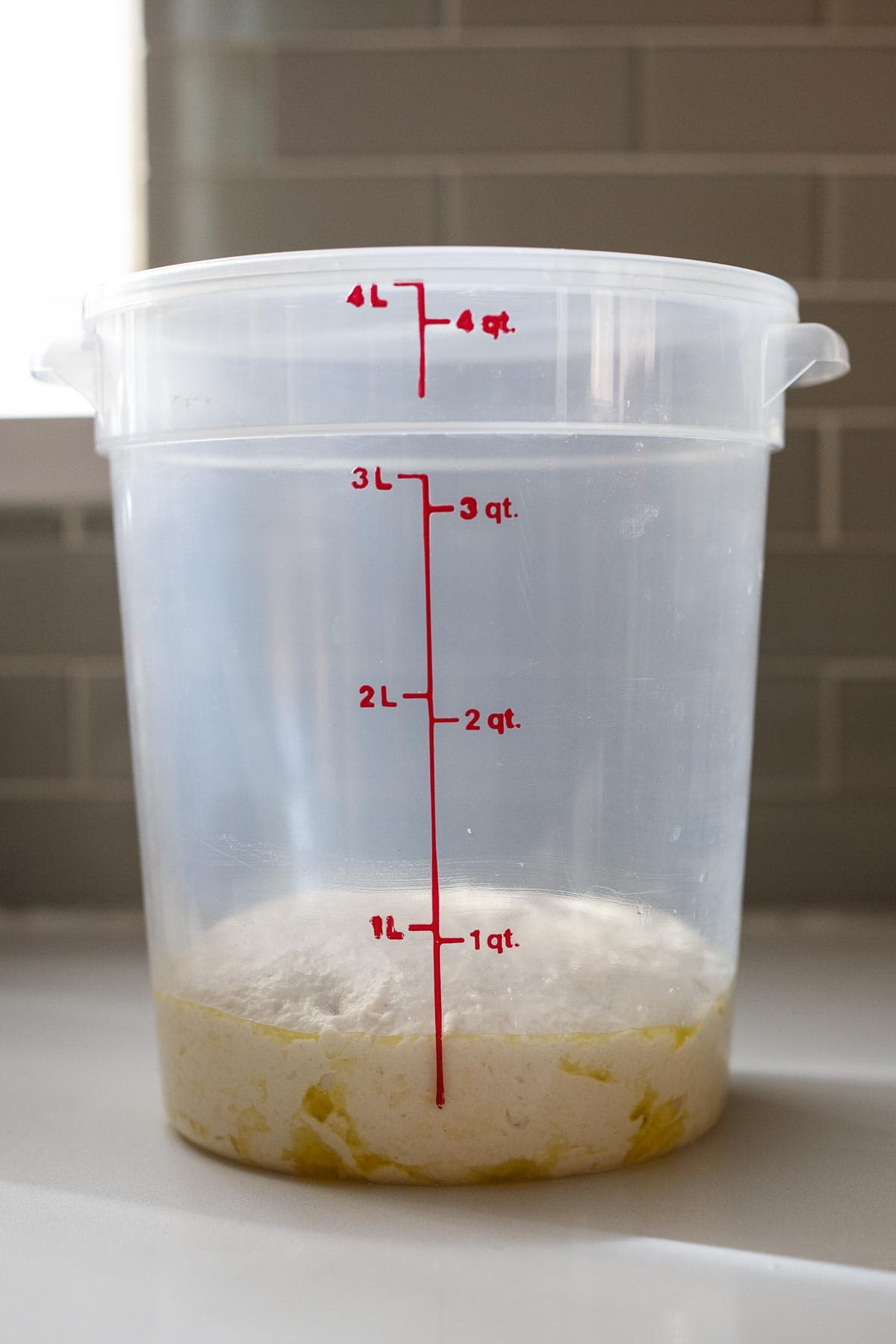 Storing the pizza dough in a tall sided container. 
