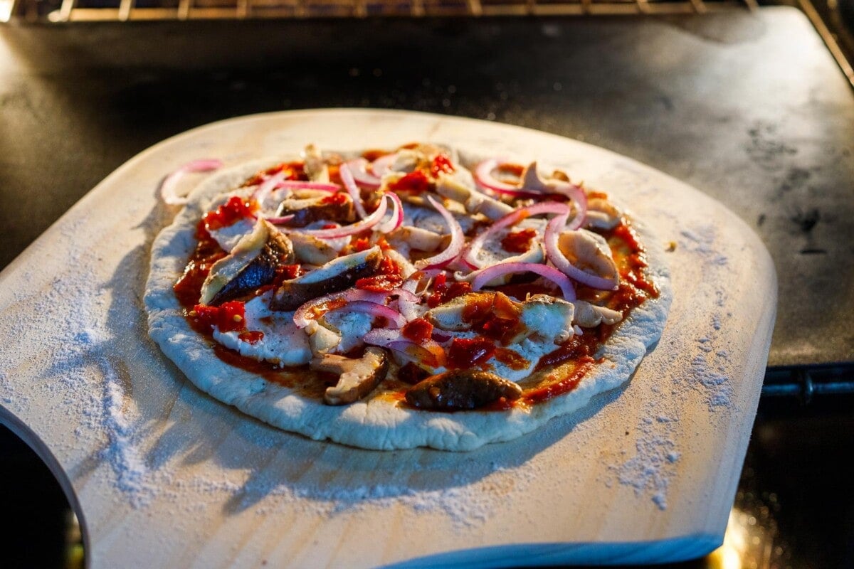 Sliding the pizza from the peel to the pizza stone in the oven. 