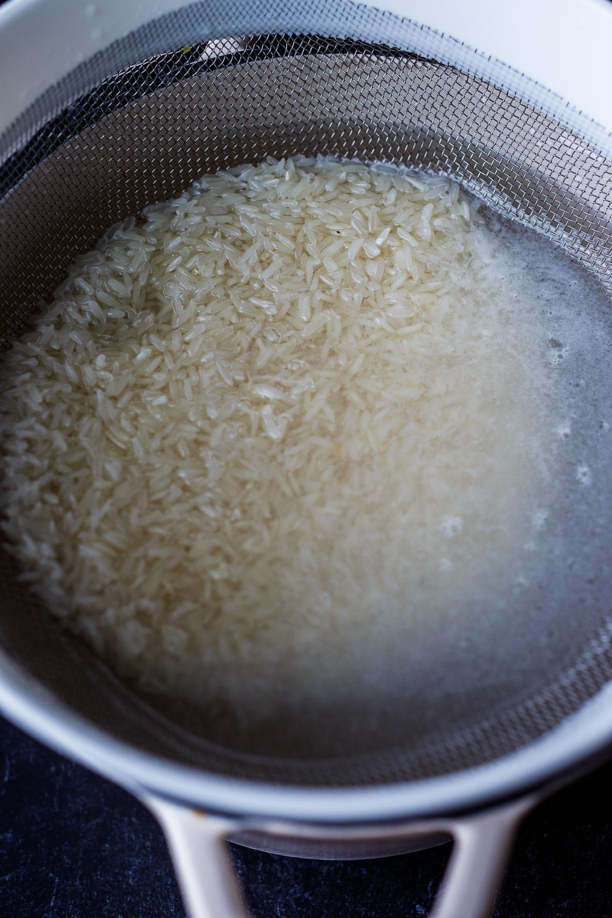 Washing rice in a mesh strainer.