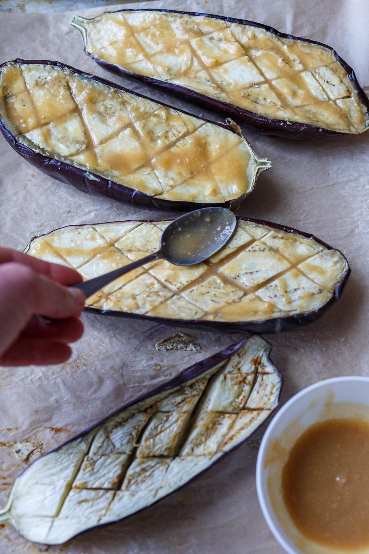 Spooning glaze on the baked eggplants.