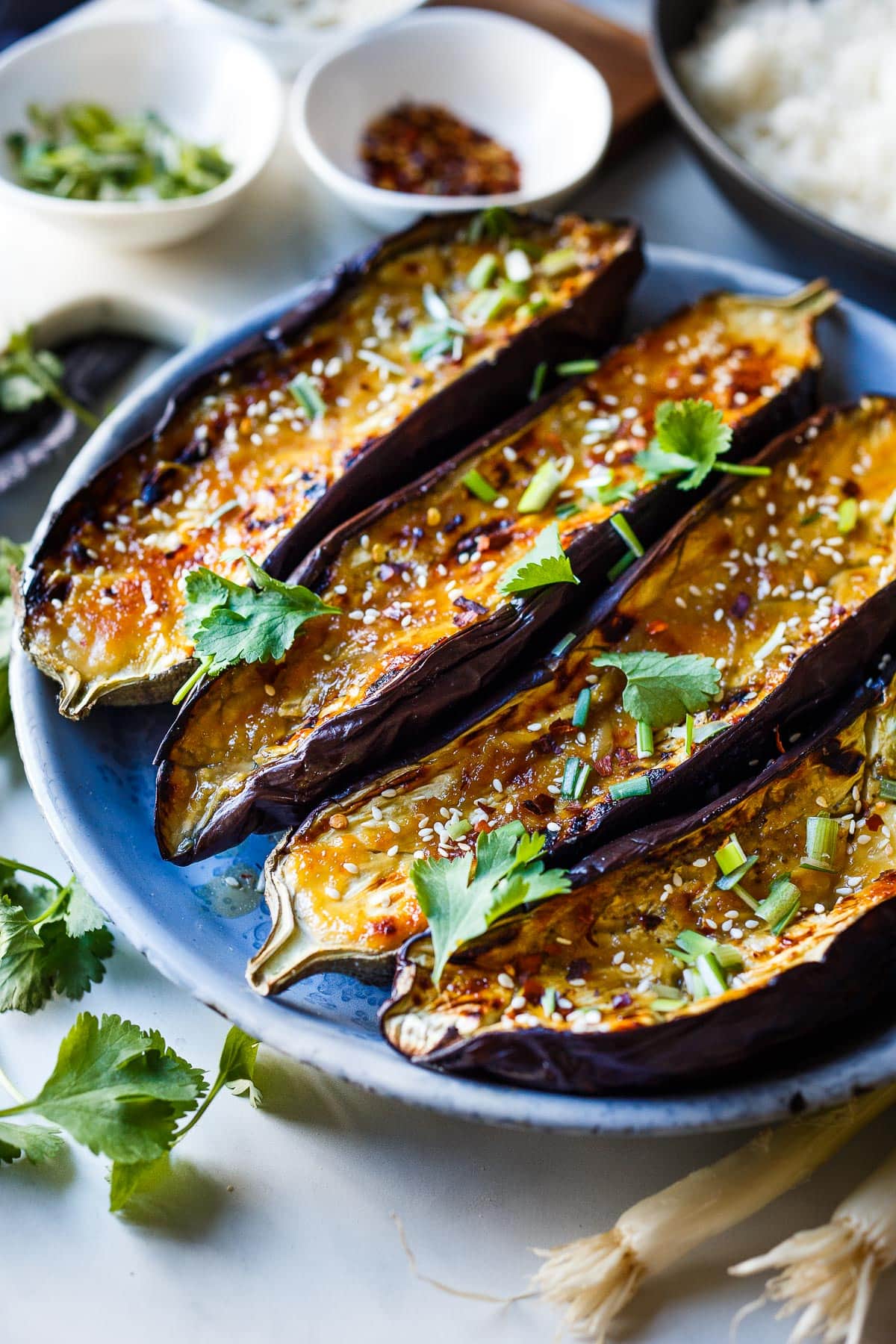 Miso glazed Eggplant with scallions and sesame seeds on a plate.