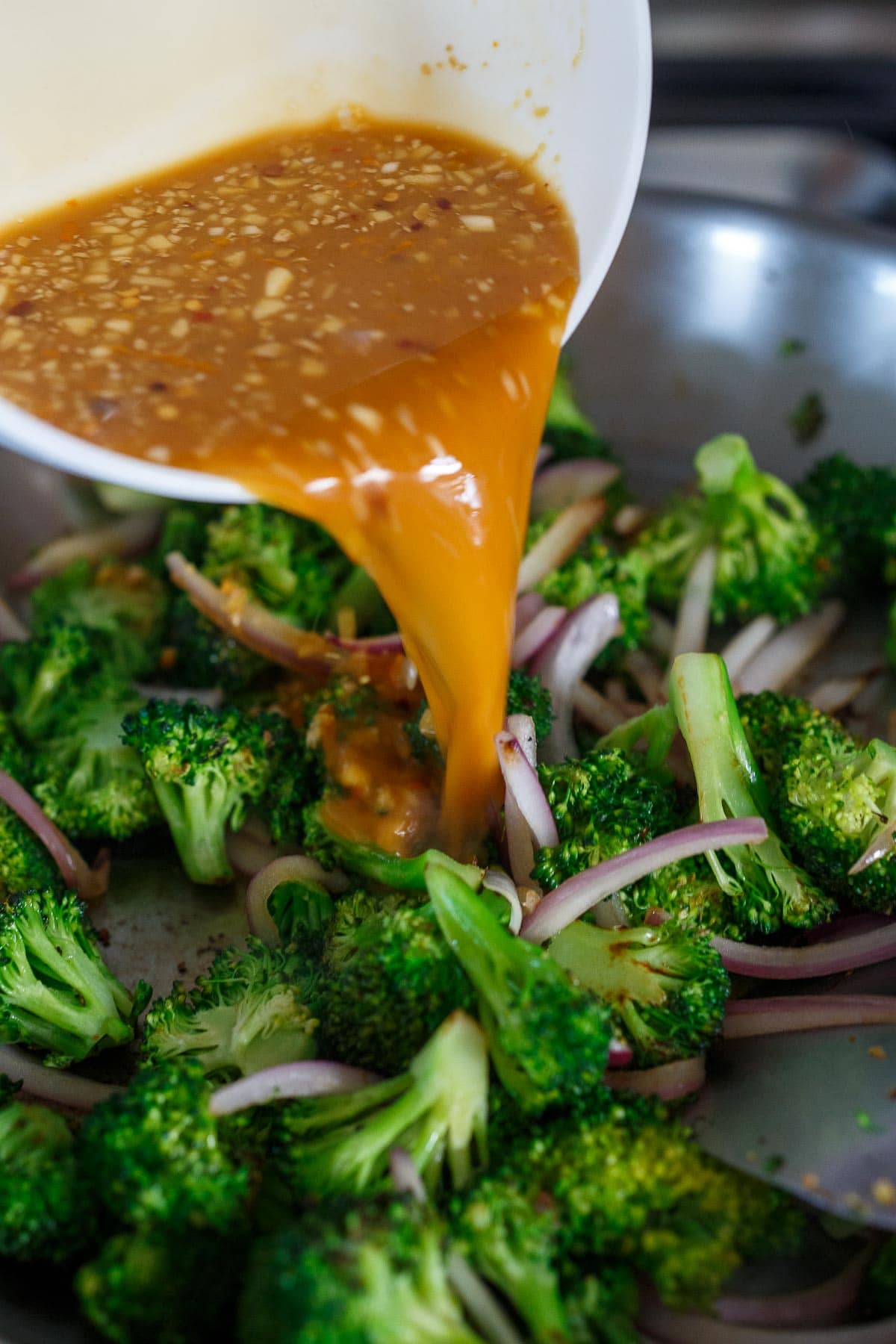 Pouring sauce into broccoli.