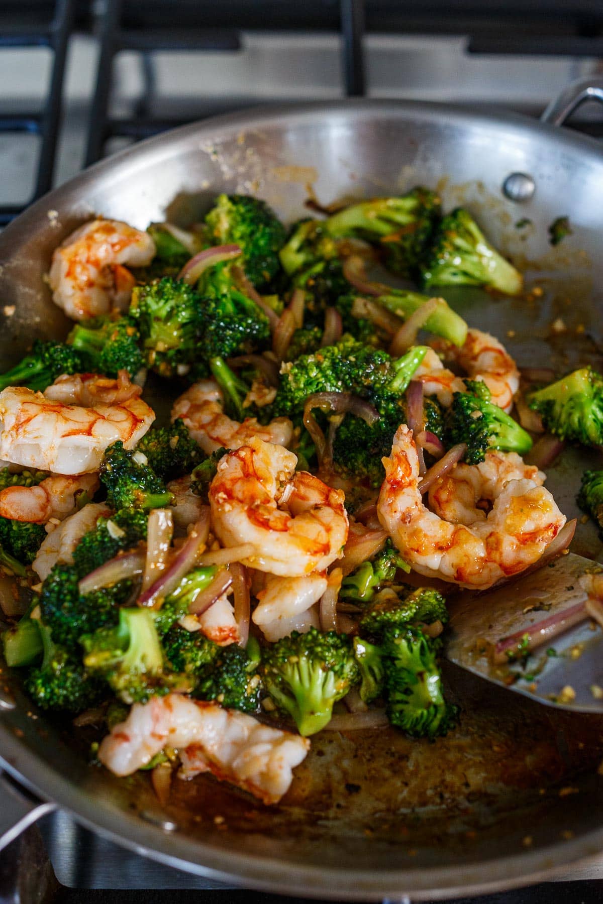 Mixing shrimp with broccoli and sauce.
