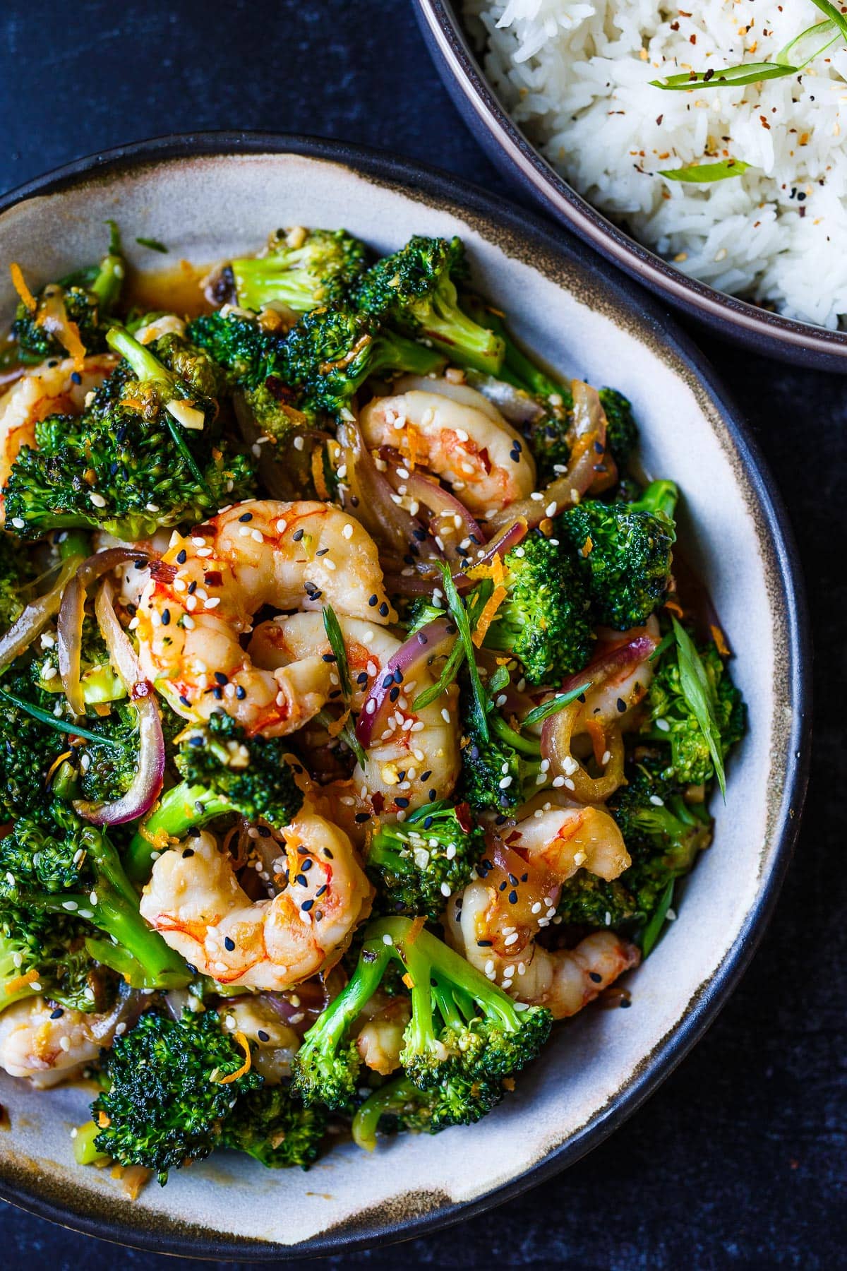 Shrimp Stir Fry with broccoli florets in a flavorful, fresh orange ginger sauce. in a bowl with rice not he side. 