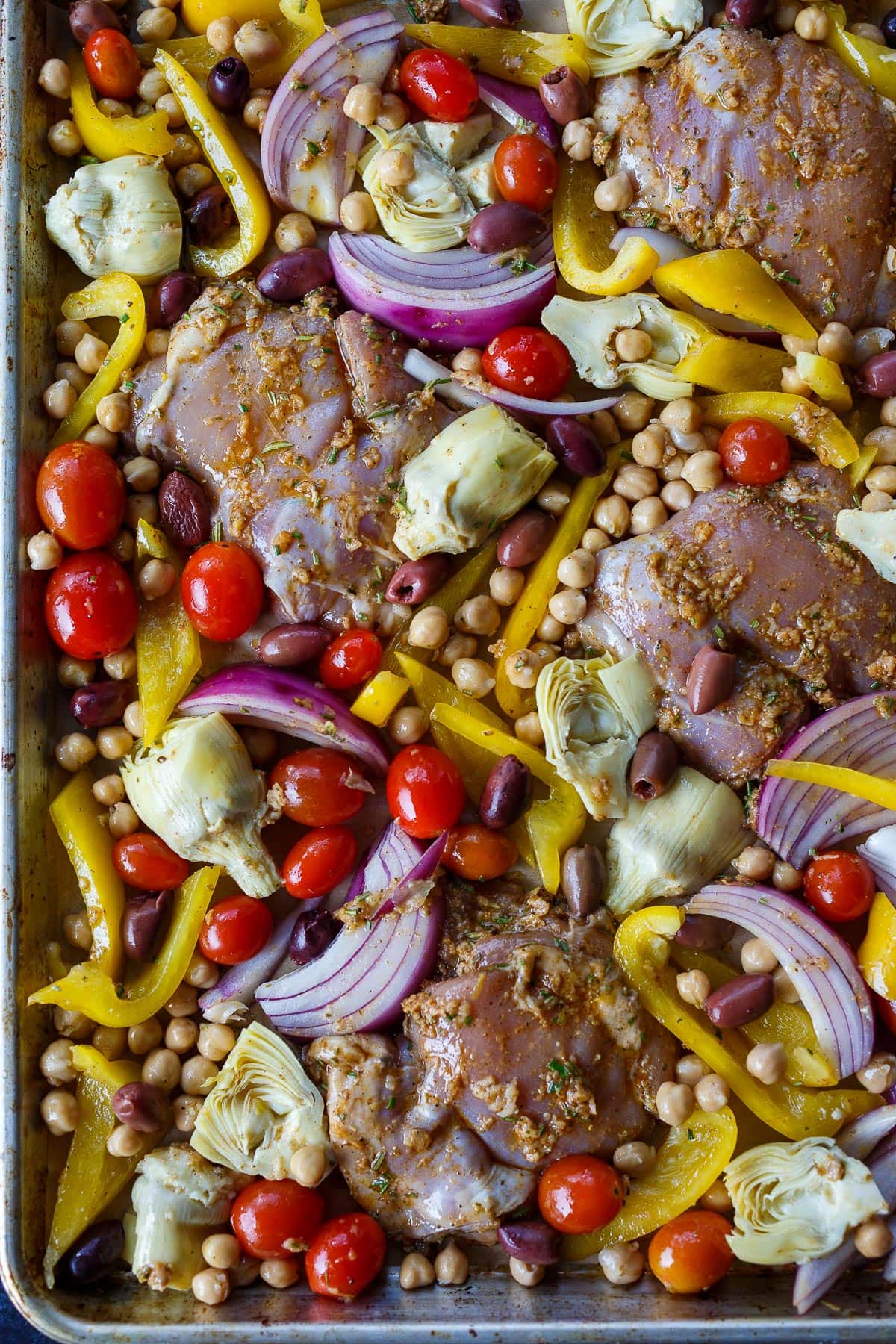 Marinated chicken and vegetables on a sheet pan.