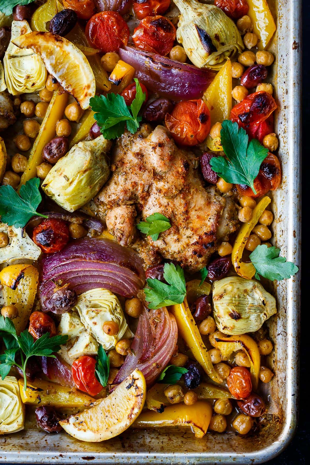 Mediterranean Chicken with veggies, chickpeas, olives and herbs. A delicious sheet pan dinner that is easy to make and easy to clean up! 