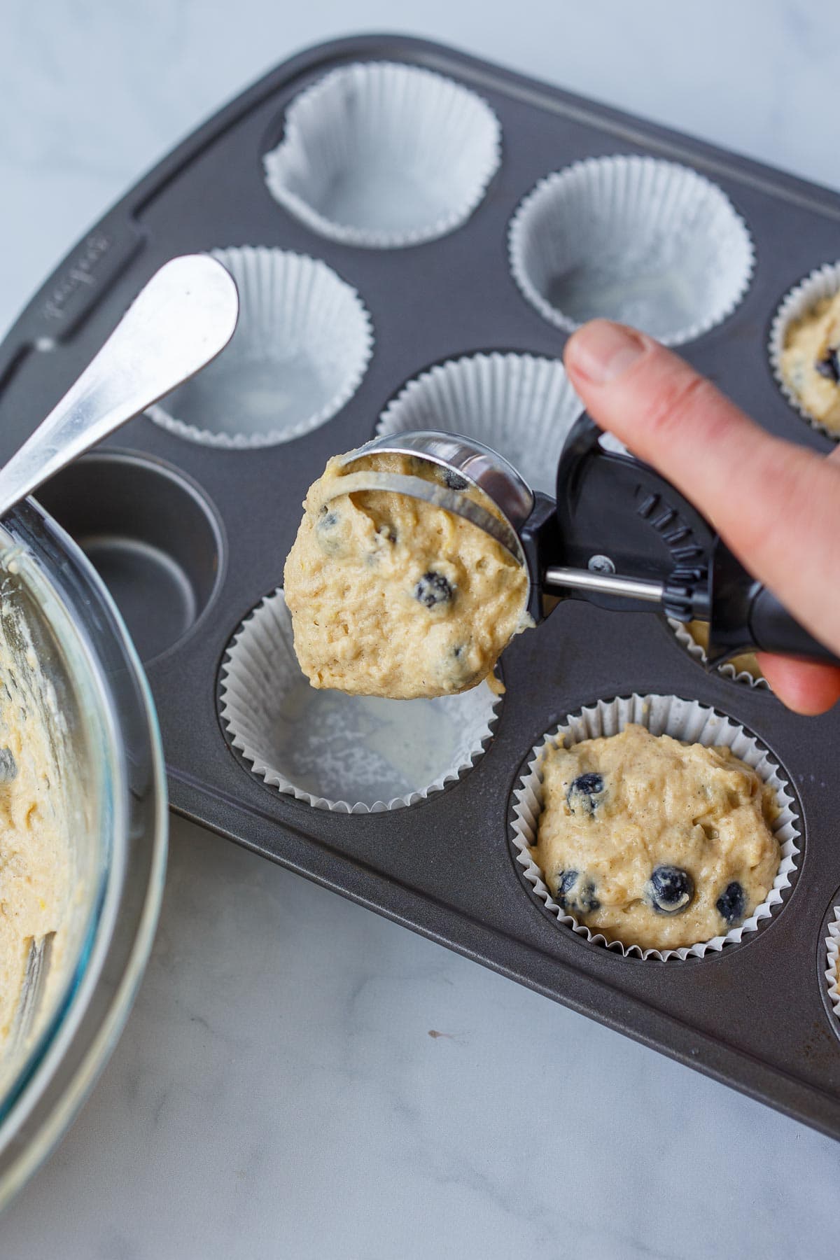 Scooping the batter into muffin tins.