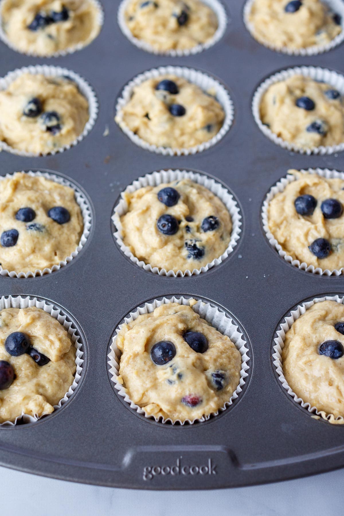 Muffin tin filled with blueberry muffin batter.