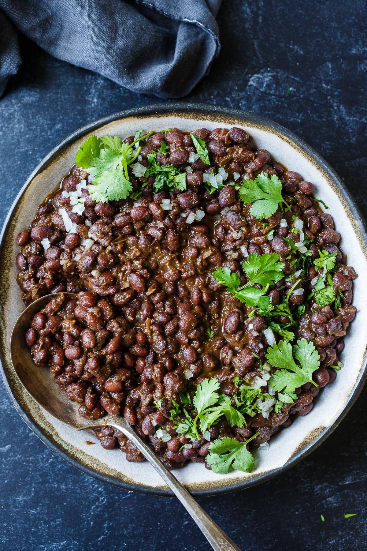 Cuban Black beans in a serving dish with onion and cilantro. 
