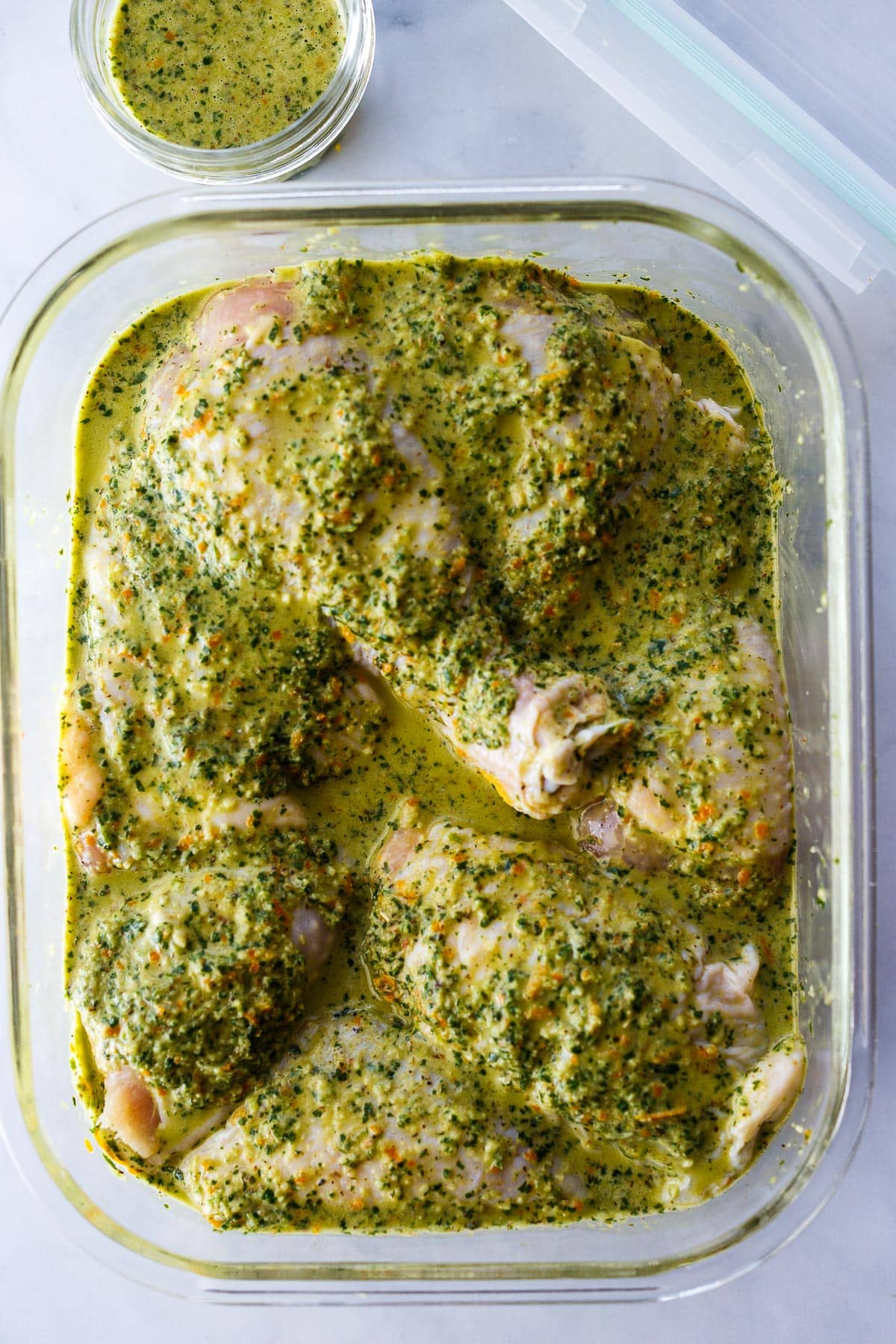 Chicken marinading in a glass container.