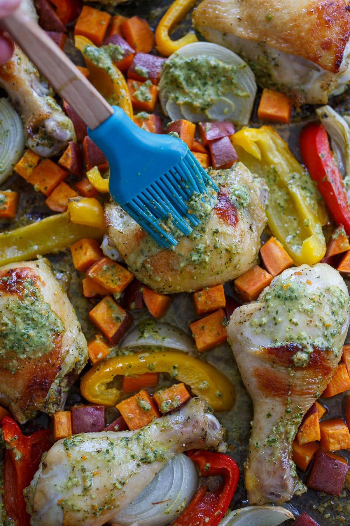 Brushing marinade over the chicken and veggies.