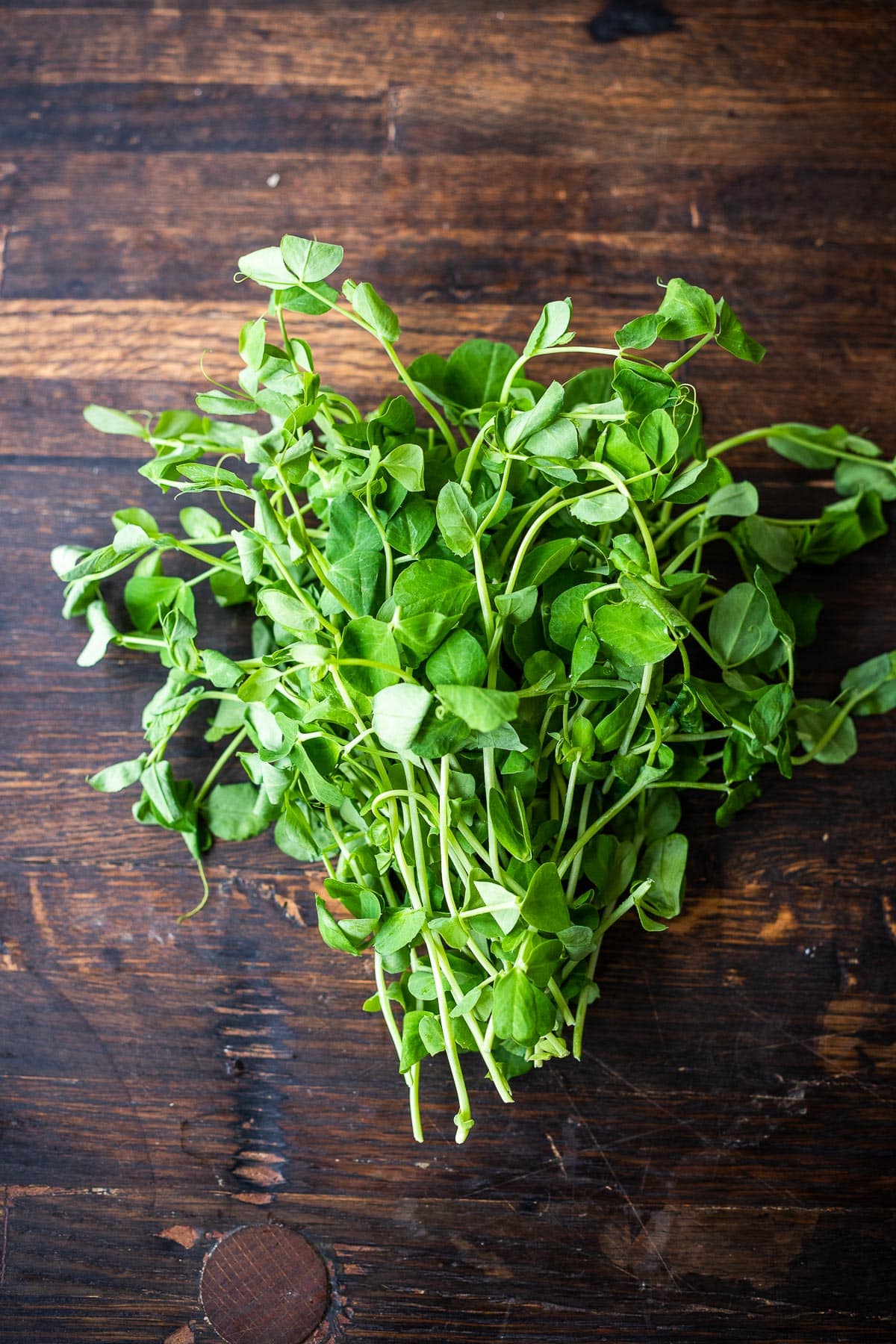 pea shoots on wood surface.