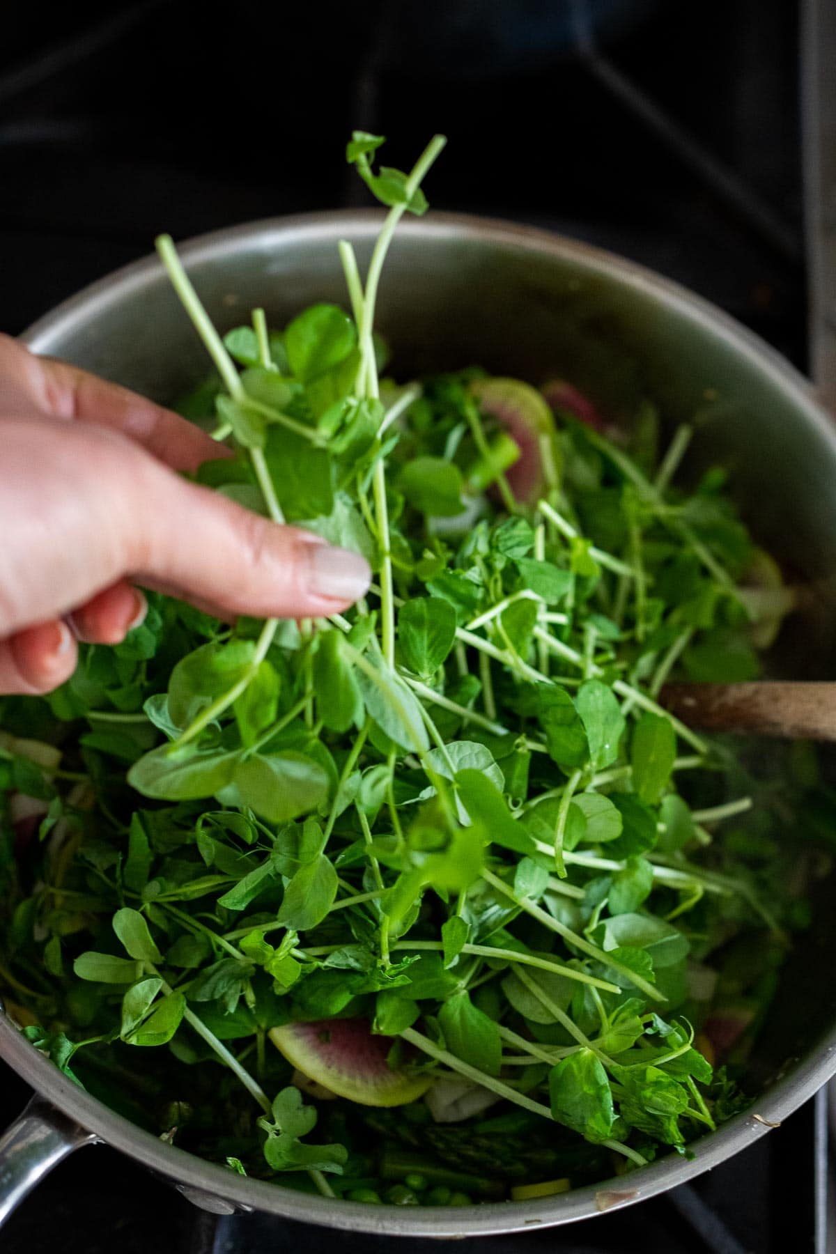 adding pea shoots to the pasta.