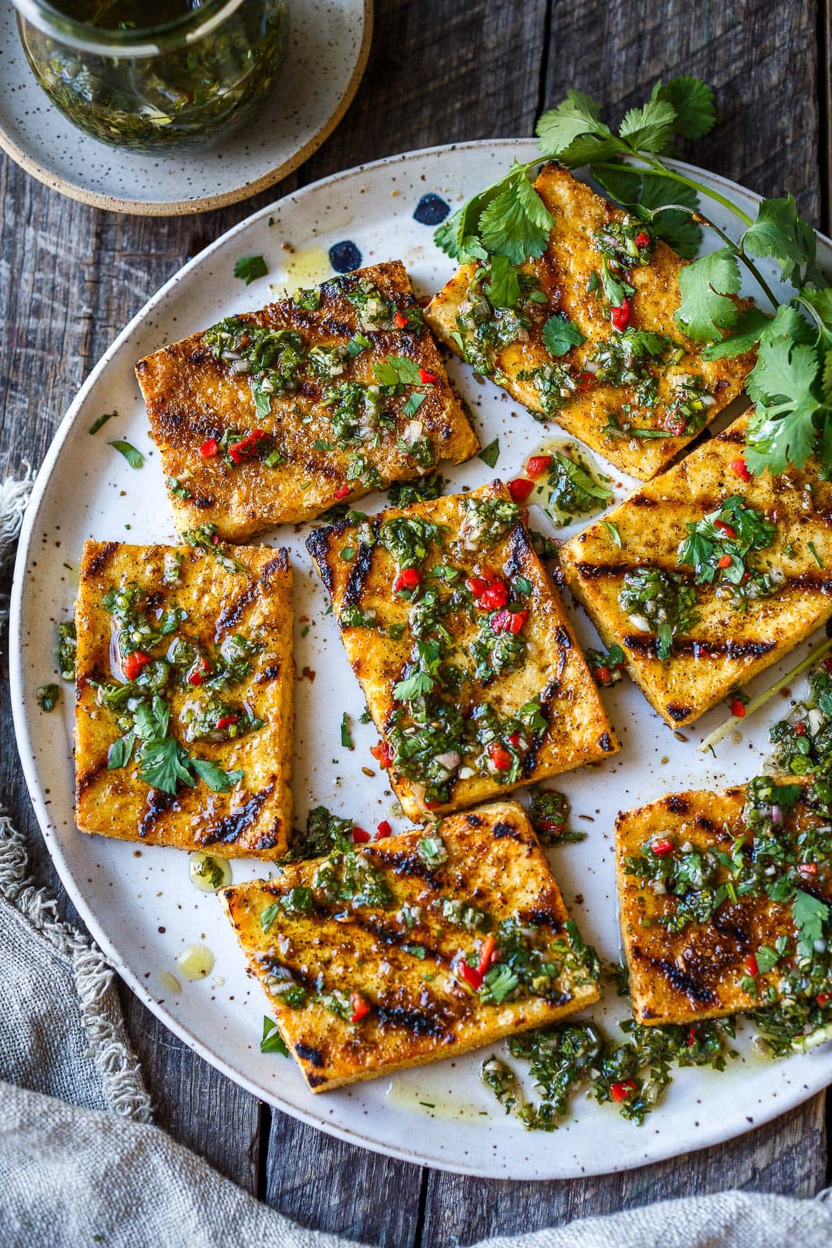 Grilled tofu on a platter with chimichurri sauce.