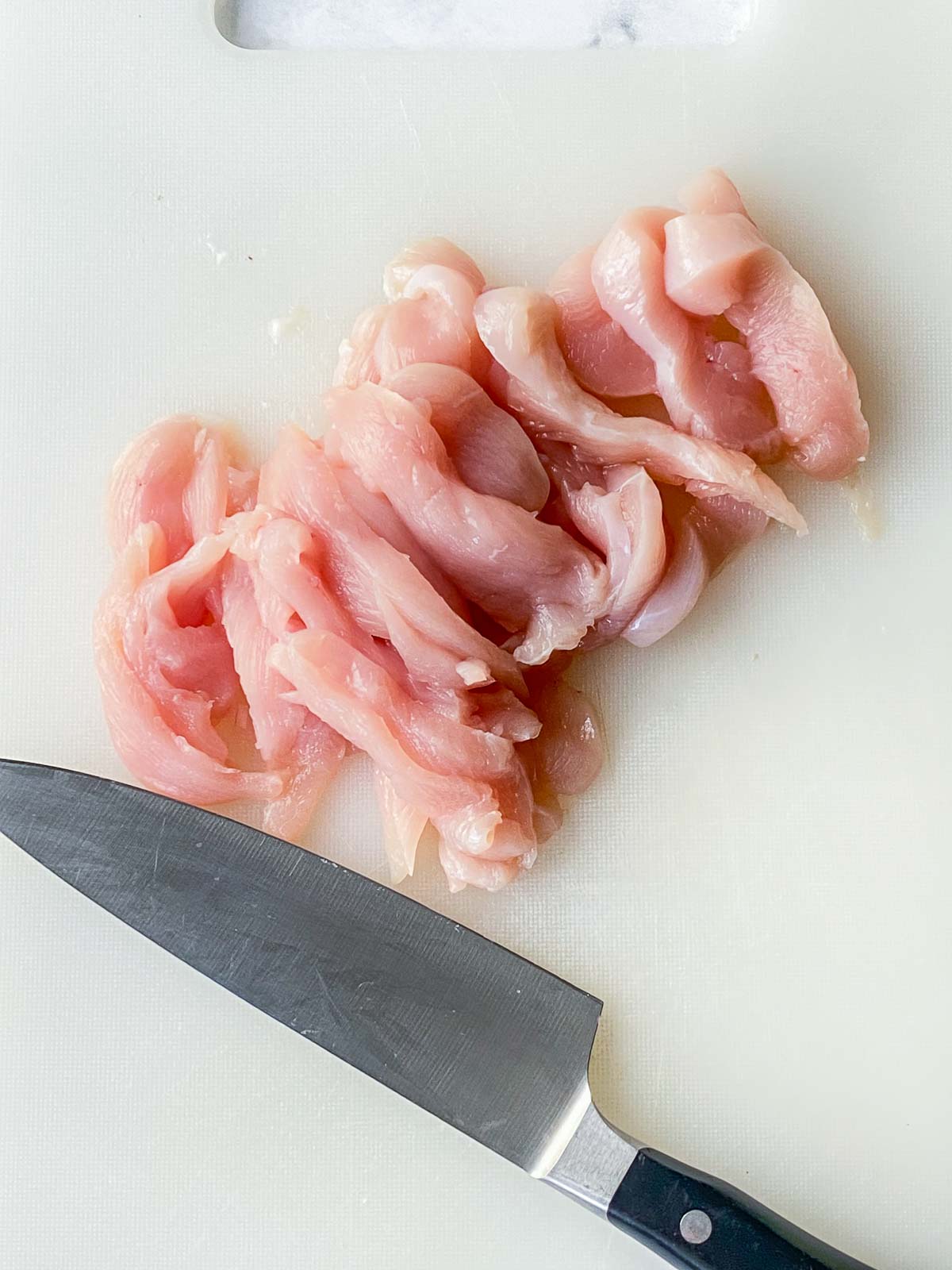 slicing chicken into thin strips.
