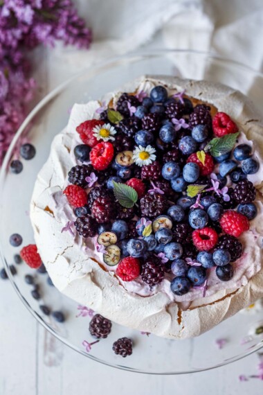 Pavlova with fresh berries and lofty whip cream. A light and airy dessert perfect for celebrations and gatherings. With a little planning ahead, this is easier than you may think!  