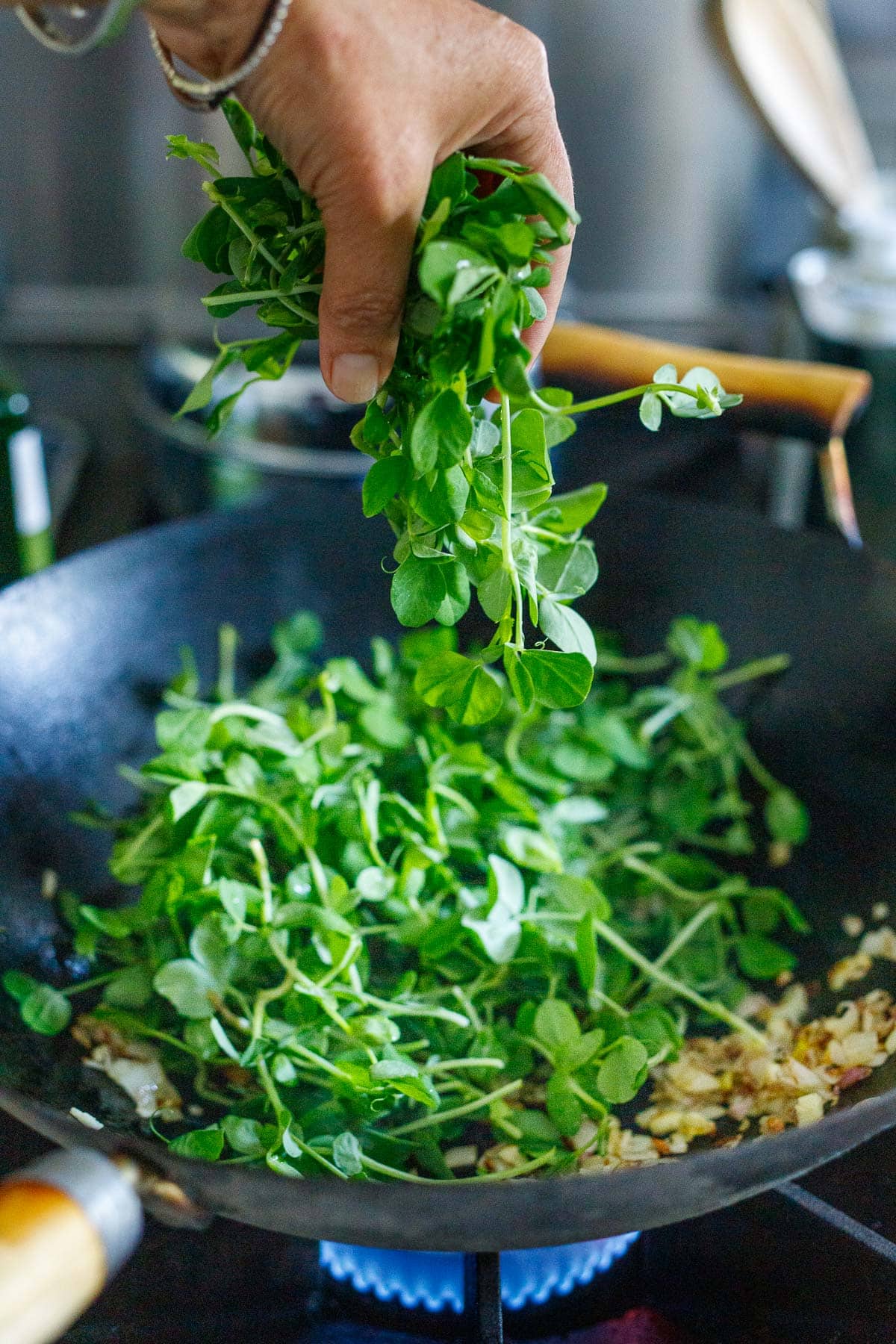 Adding pea shoots to the wok. 