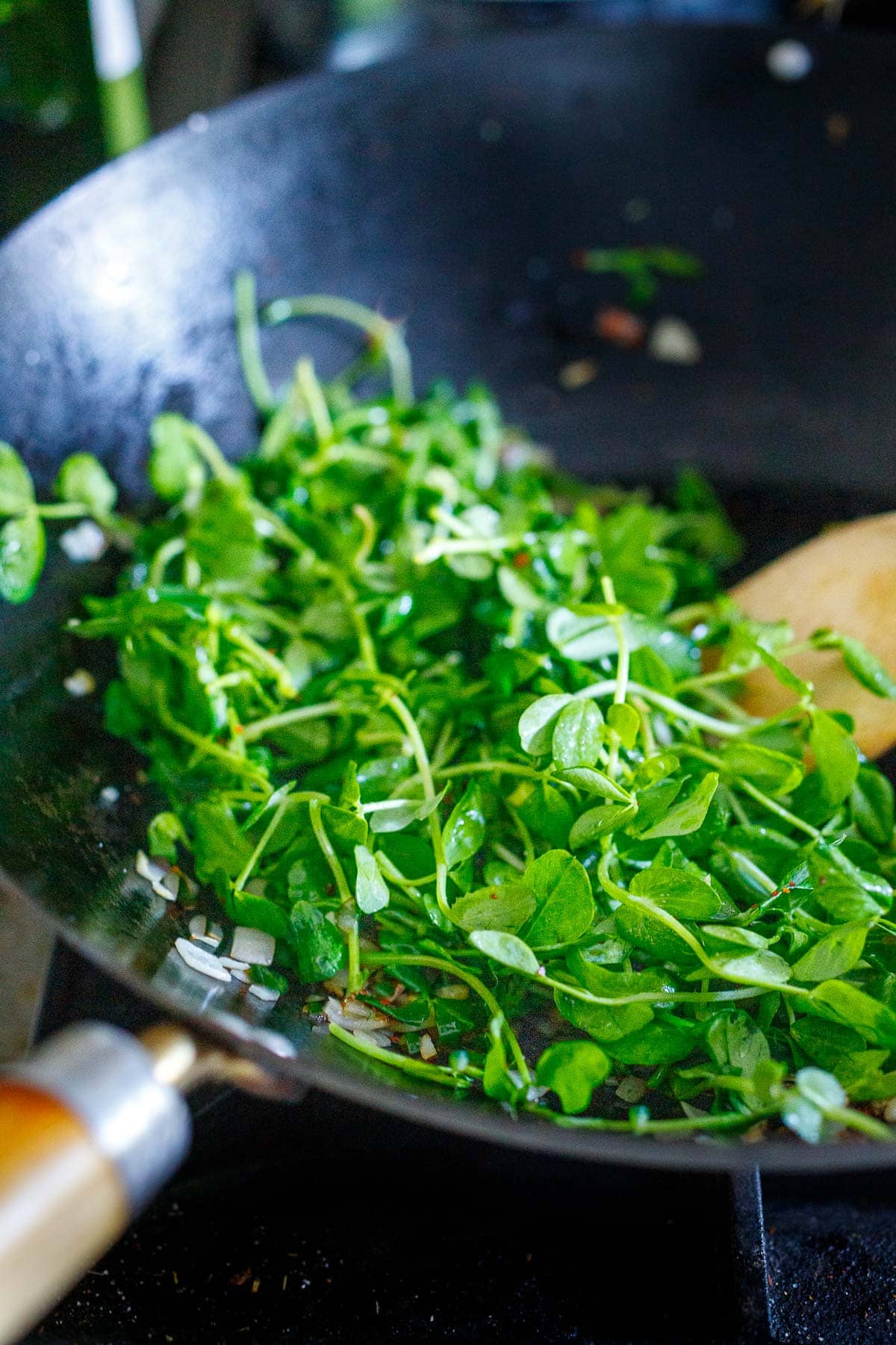 Stir frying pea shoots.