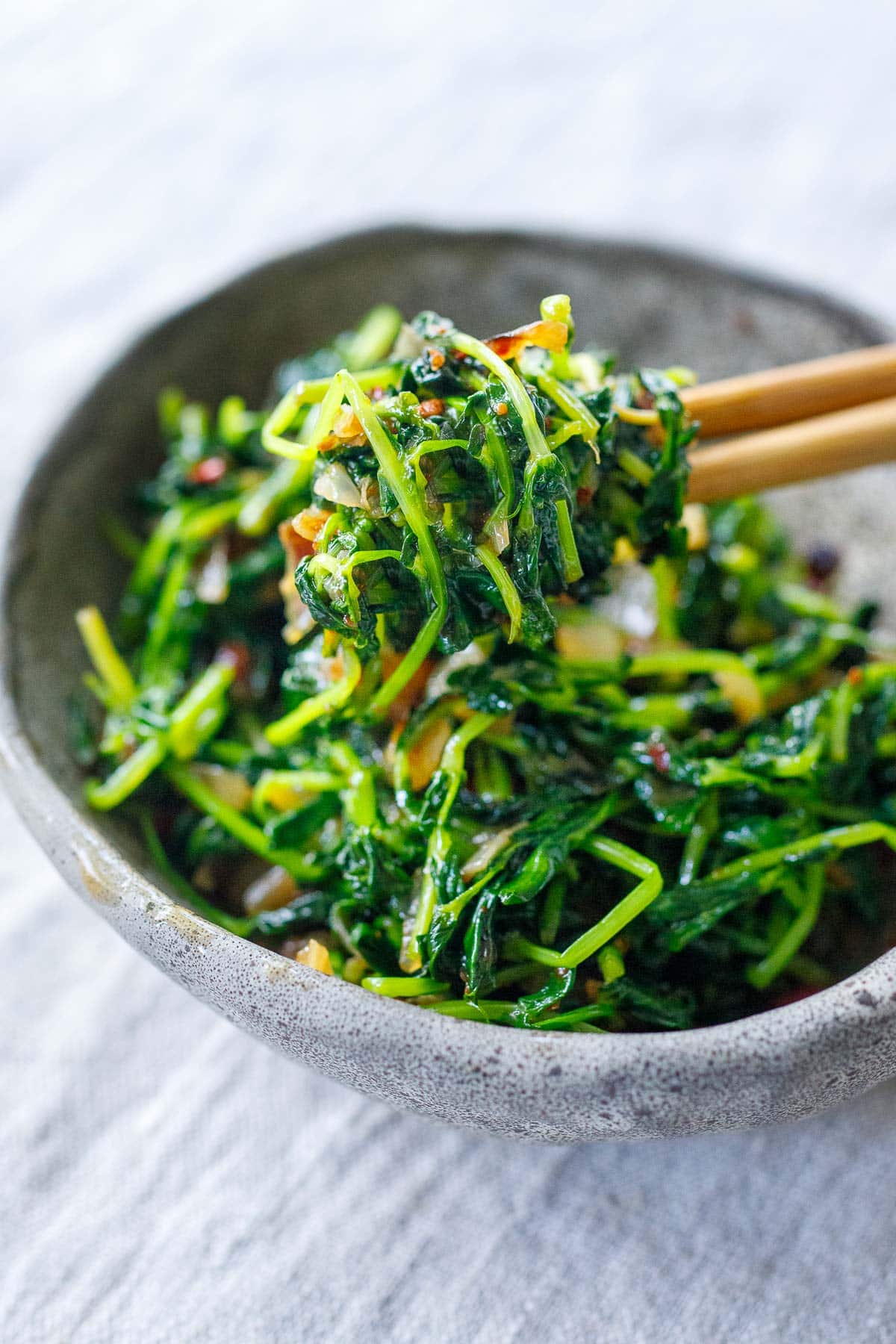 Wondering what to do with young pea shoots? These stir fried pea shoots are incredibly easy to make and full of flavor; a tasty spring side dish that comes together in 15 minutes!