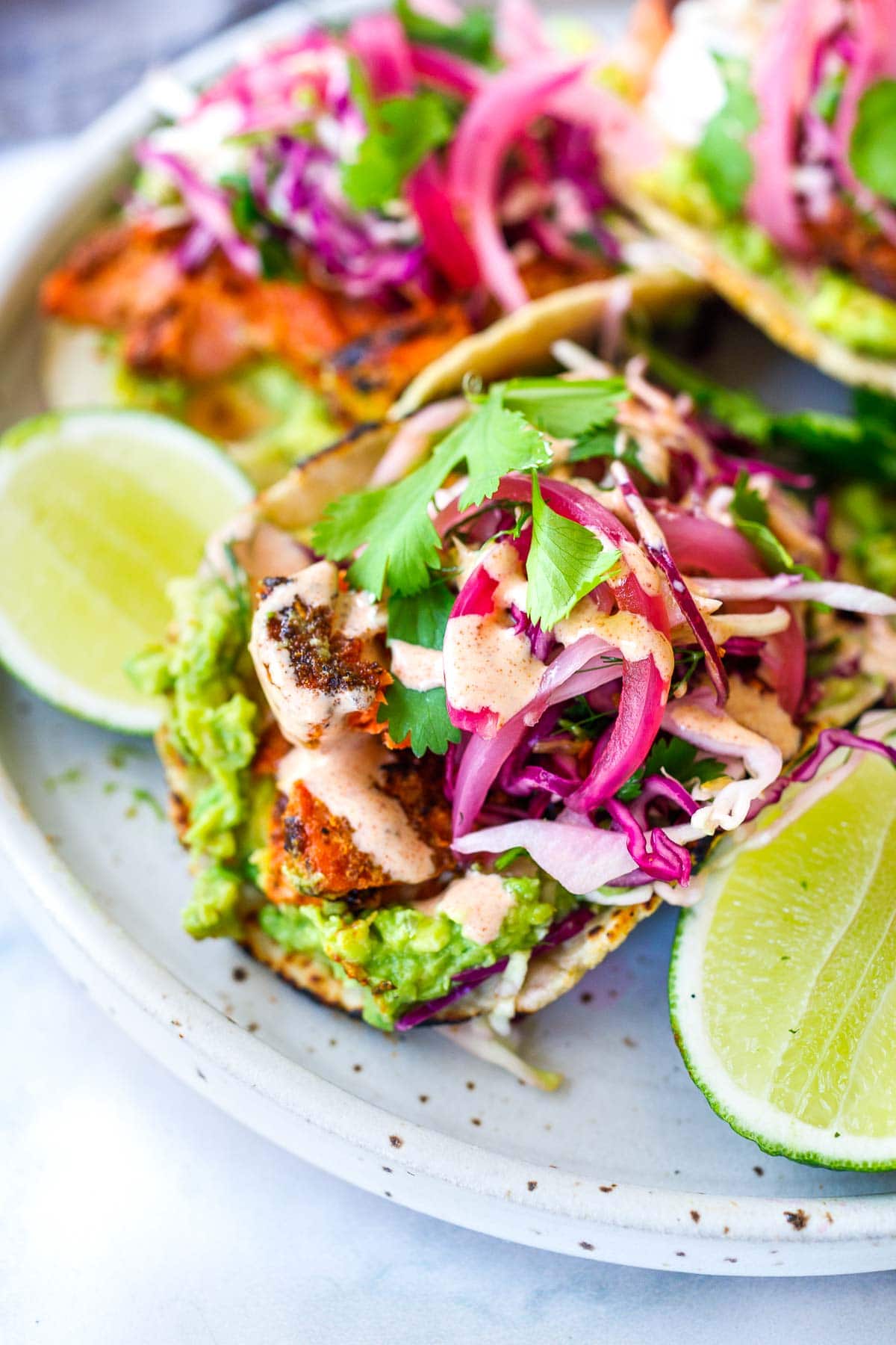 Salmon tacos loaded up with avocado, pickled onions, cilantro, taco slaw and creamy taco sauce.