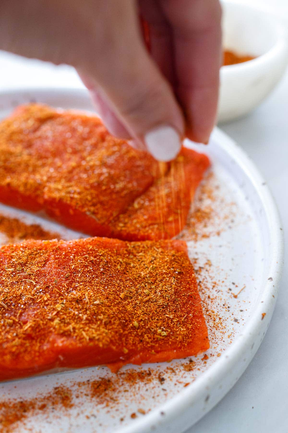 Seasoning the salmon with cajun spice.