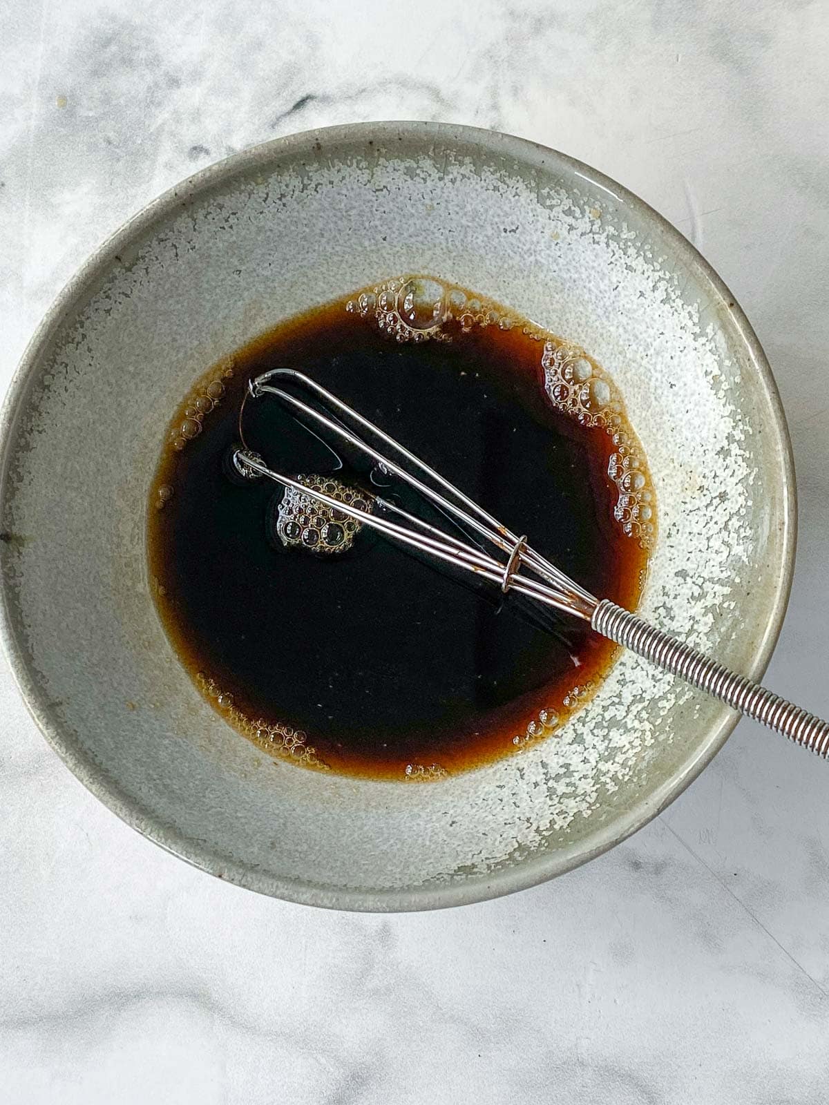 whisking the pad thai sauce in a bowl.