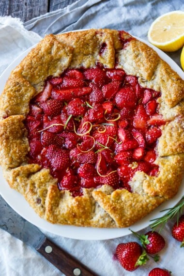 This Strawberry Galette is bright, cheery and full of springtime flavor. Lemon and rosemary perfectly compliment the sweet berries. A rustic flaky rye pastry crust encloses the succulent filling.
