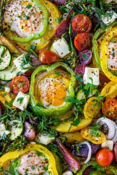 These Baked Eggs are so fun and easy to make! Eggs are baked in the oven on a sheet pan cradled inside rings of bell pepper along with roasted potatoes, zucchini, and tomatoes. Top them with feta and fresh herbs.