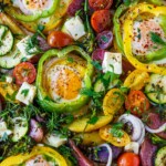 These Baked Eggs are so fun and easy to make! Eggs are baked in the oven on a sheet pan cradled inside rings of bell pepper along with roasted potatoes, zucchini, and tomatoes. Top them with feta and fresh herbs.