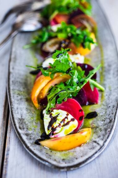 A beautiful Burrata Salad with tomatoes, beets, basil and flavorful basil oil, drizzled with balsamic glaze - perfect for summer dinners and gatherings. Elegant and flavorful.