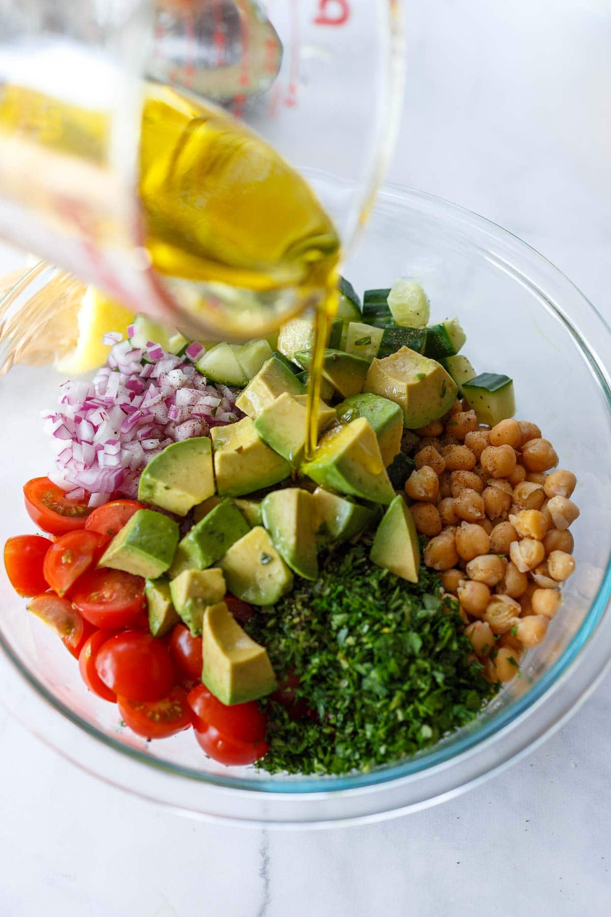 Pouring olive oil over Chickpea Salad.