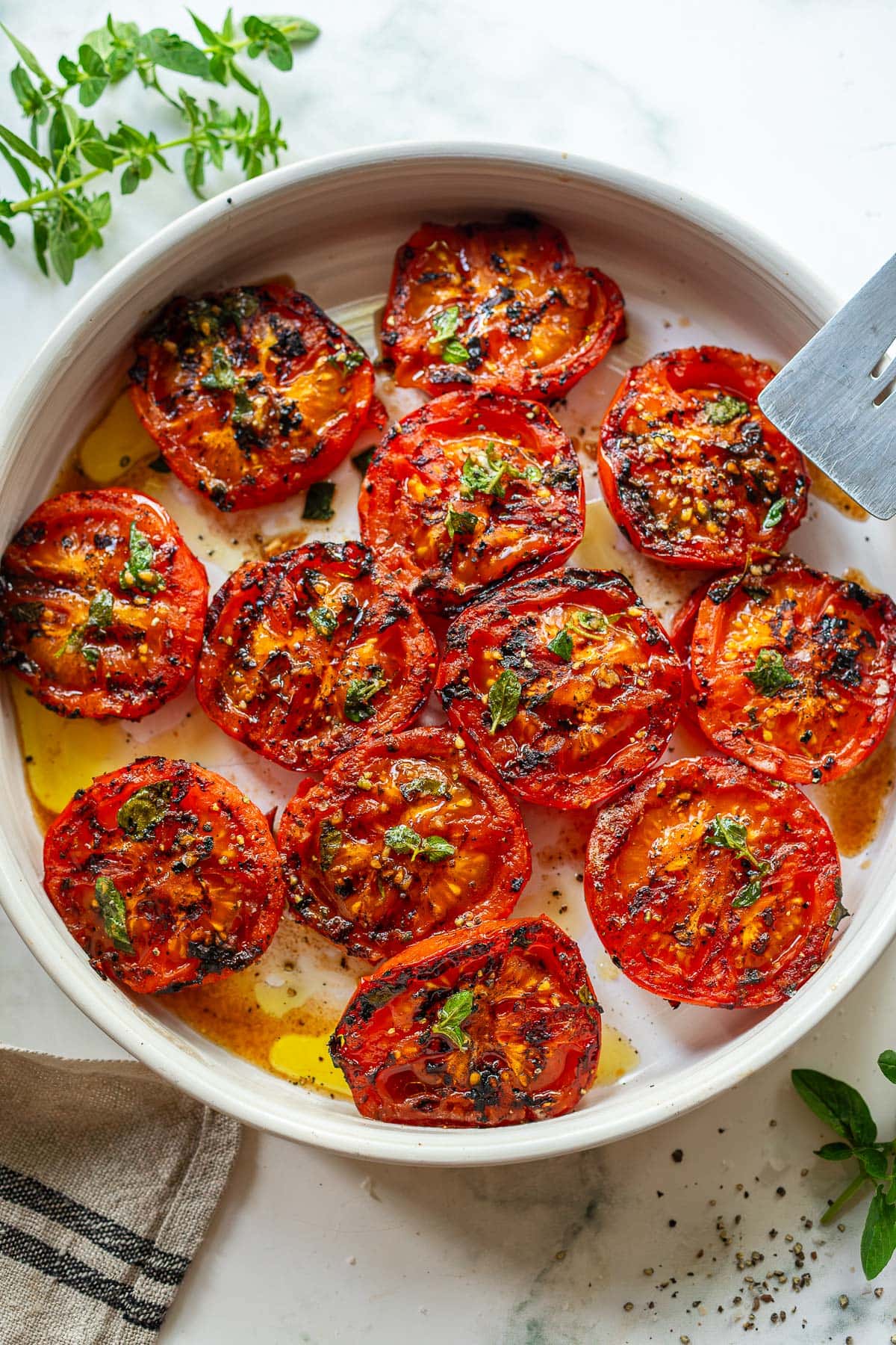 grilled tomatoes with oregano in a serving dish. 