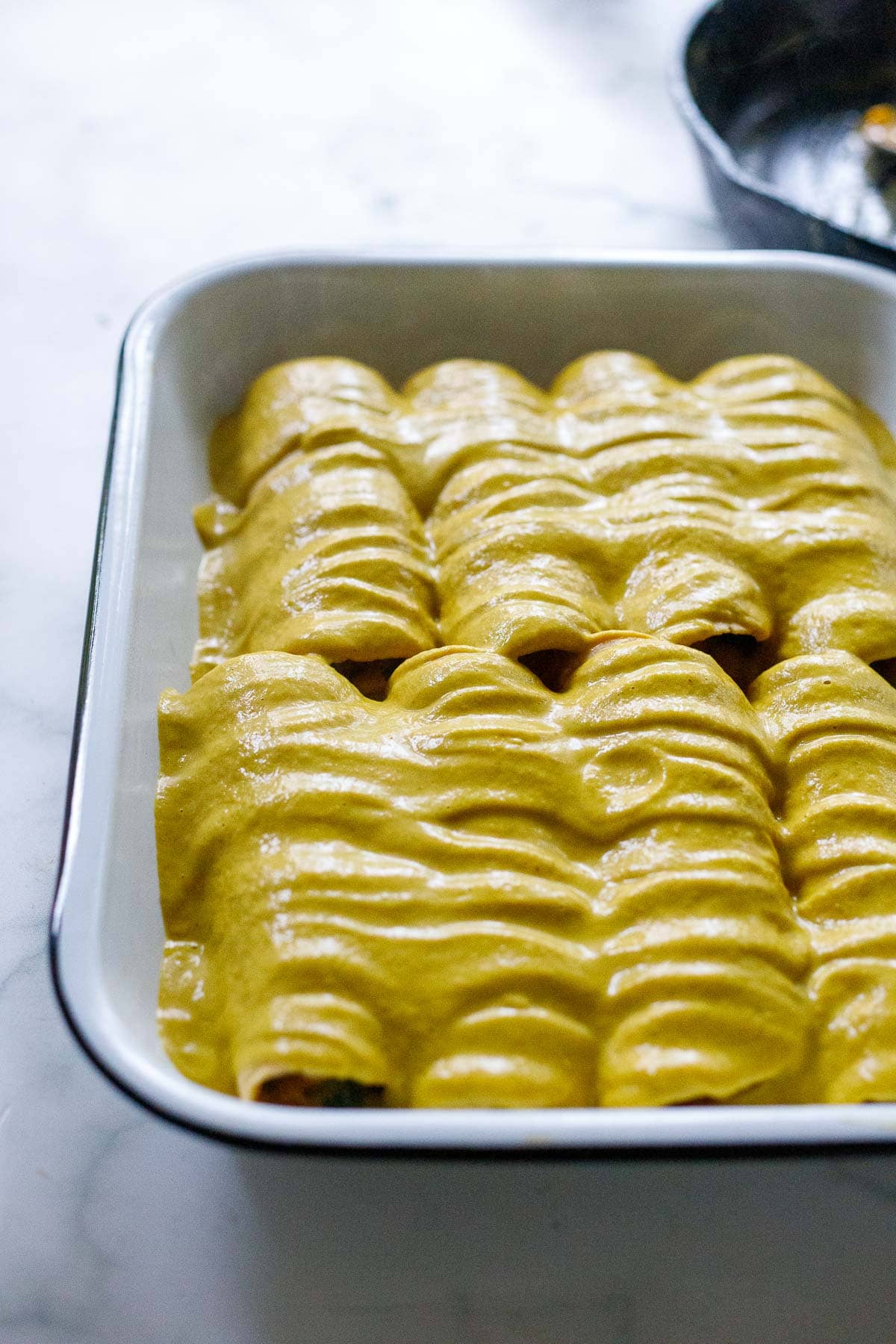 Yellow mole sauce over the enchiladas