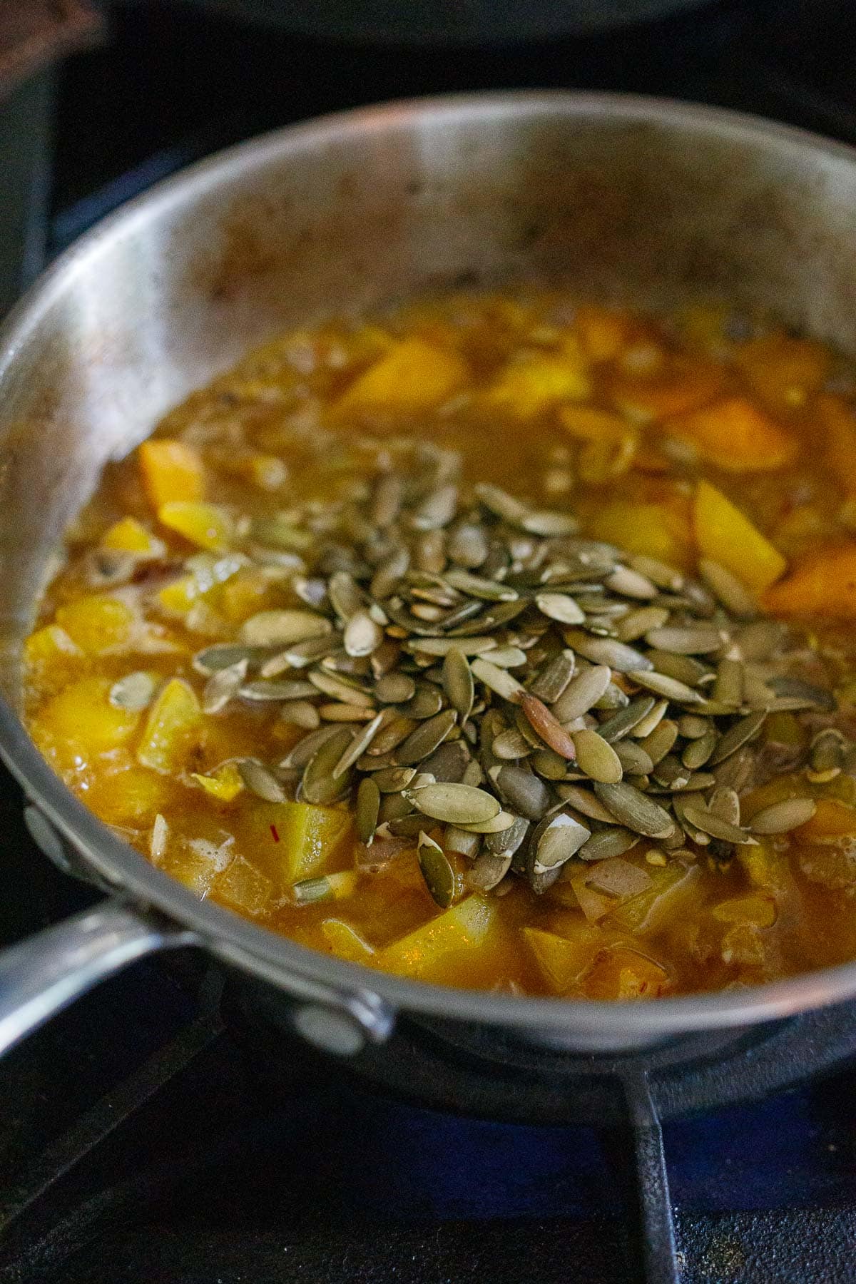 Adding the pumpkin seeds to the yellow mole sauce.