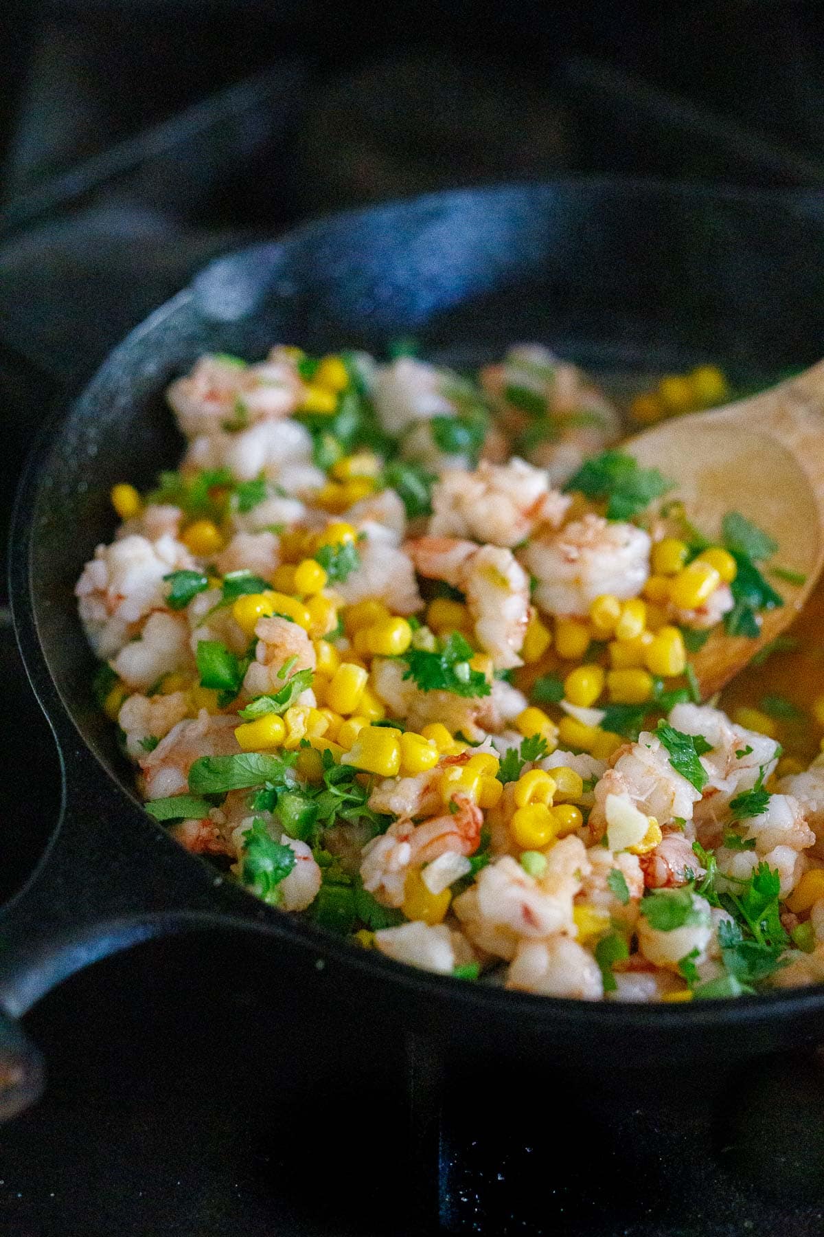 Adding corn and cilantro to the shrimp. 