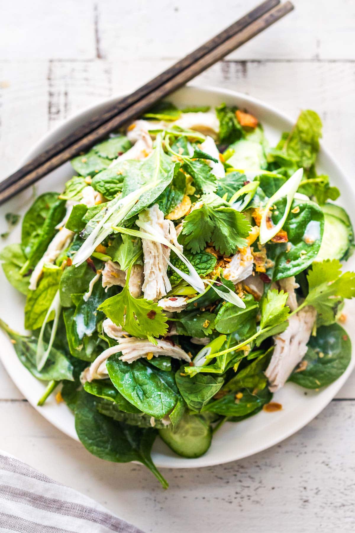 A tasty recipe for Thai Chicken Salad with baby spinach, cucumber, mint, cilantro, and scallions with crispy shallots. A flavorful entree salad perfect for warm summer nights.