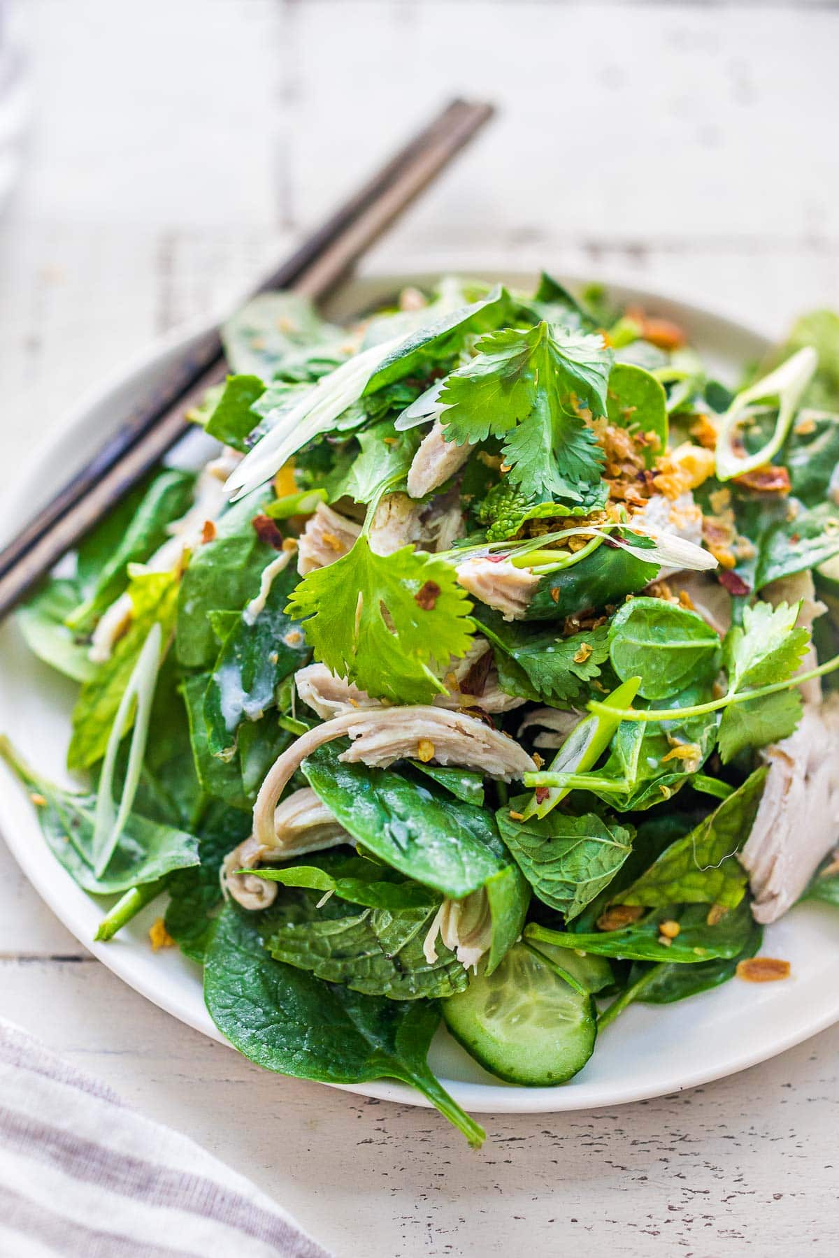 A tasty recipe for Thai Chicken Salad with baby spinach, cucumber, mint, cilantro, and scallions with crispy shallots. A flavorful entree salad perfect for warm summer nights. 