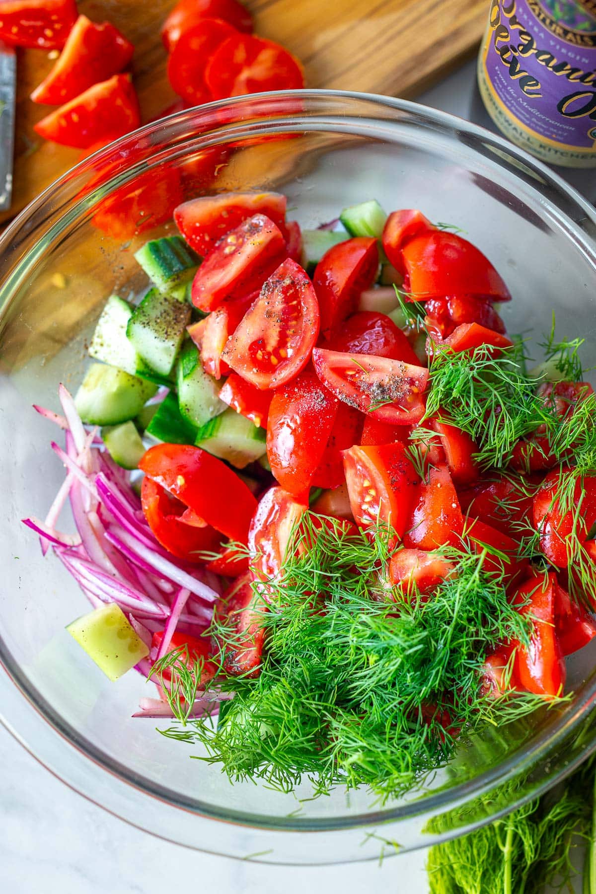 Tomato & cucumber salad ingredients- Tomatoes, cucumbers in a bowl with onions and dill for Cucumber Tomato Salad.