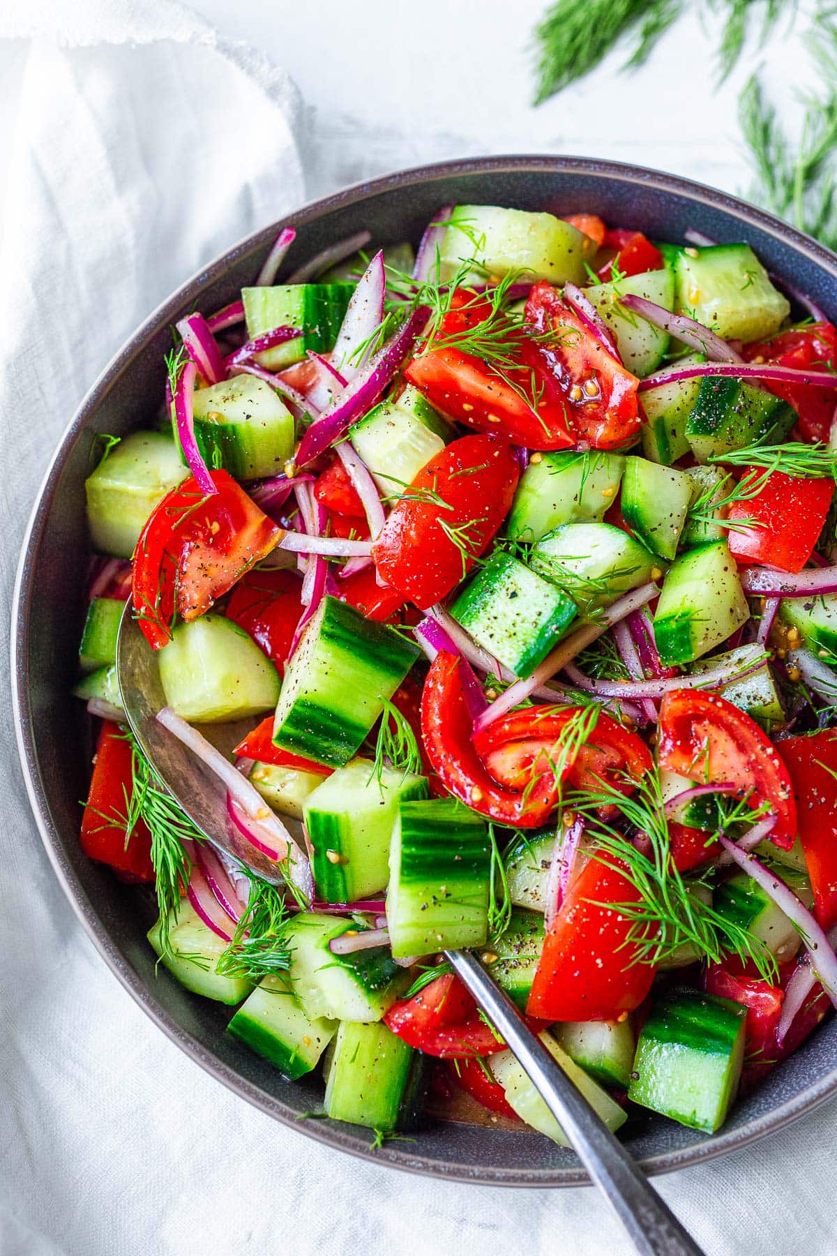 Looking for a light and healthy summer salad? This quick & easy Cucumber Tomato Salad is fresh and light, made with vine-ripe tomatoes and juicy cucumbers, slivers of red onion, and fresh dill, tossed in a red-wine vinaigrette.