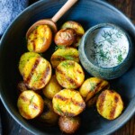 grilled potatoes in a bowl with creamy dill sauce